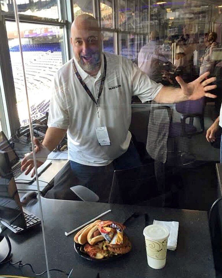 In the DJ booth at M&T Bank Stadium, Robert Popik shows off a plate of food he had assembled from the Ravens' employee buffet.