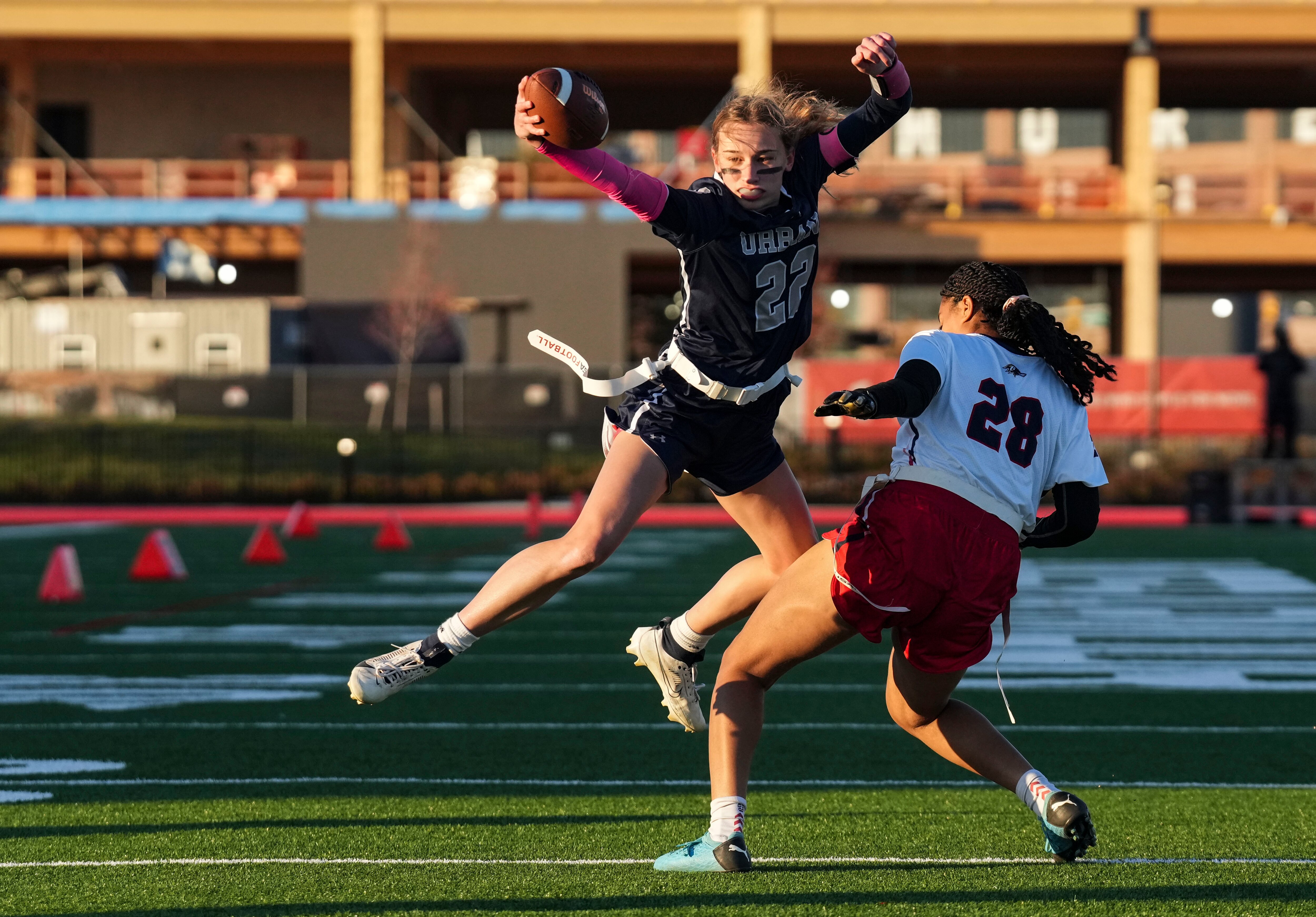 Urbana’s Ava Duerr (22) attempts to jump past Thomas Johnson’s Naima Thomas (28) during the girls flag semifinals at Under Armour’s “The Stadium at the House” in Baltimore on Wednesday.