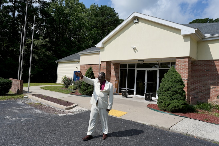 Roosevelt Toussaint, the senior pastor of the Word of Life Center church, points to empty parking spaces outside his church before a service, which he says is due to fear in the Haitian community of possible arrests and deportation in Salisbury, Md., Sunday, Aug. 2, 2026. (AP Photo/Luis Andres Henao)