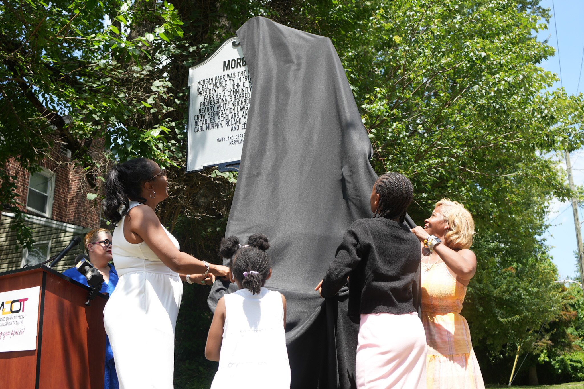 Jessica Jackson, a Morgan Park Improvement Association history executive board member and resident, unveils a new Marker commemorating the historic neighborhood with her daughters Madison Morgan, 13, and Kennedy Rose Jackson, 6.