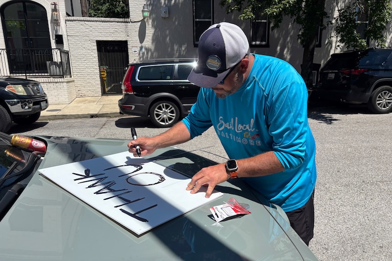 Bobby LaPin writes thank you on the back of a campaign sign the morning after his primary loss to Senate President Bill Ferguson.