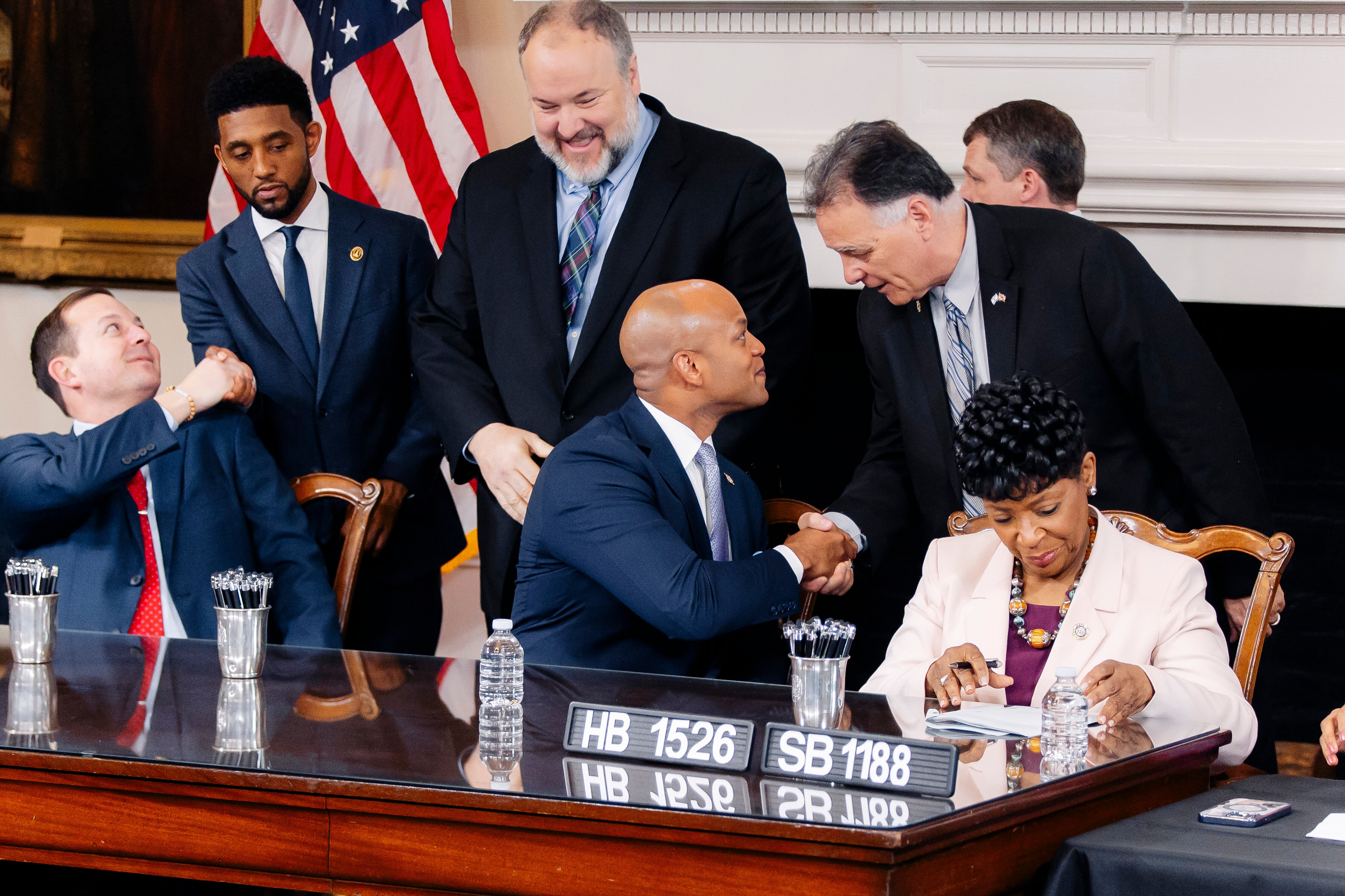 From back left, Baltimore Mayor Brandon Scott, Del. Luke Clippinger and Sen. Johnny Ray Salling stand and shake hands with Senate President Bill Ferguson, Gov. Wes Moore and House of Delegates Speaker Adrienne A. Jones during the signing of the PORT Act at the Maryland State House on Tuesday, April 9, in Annapolis, Maryland.