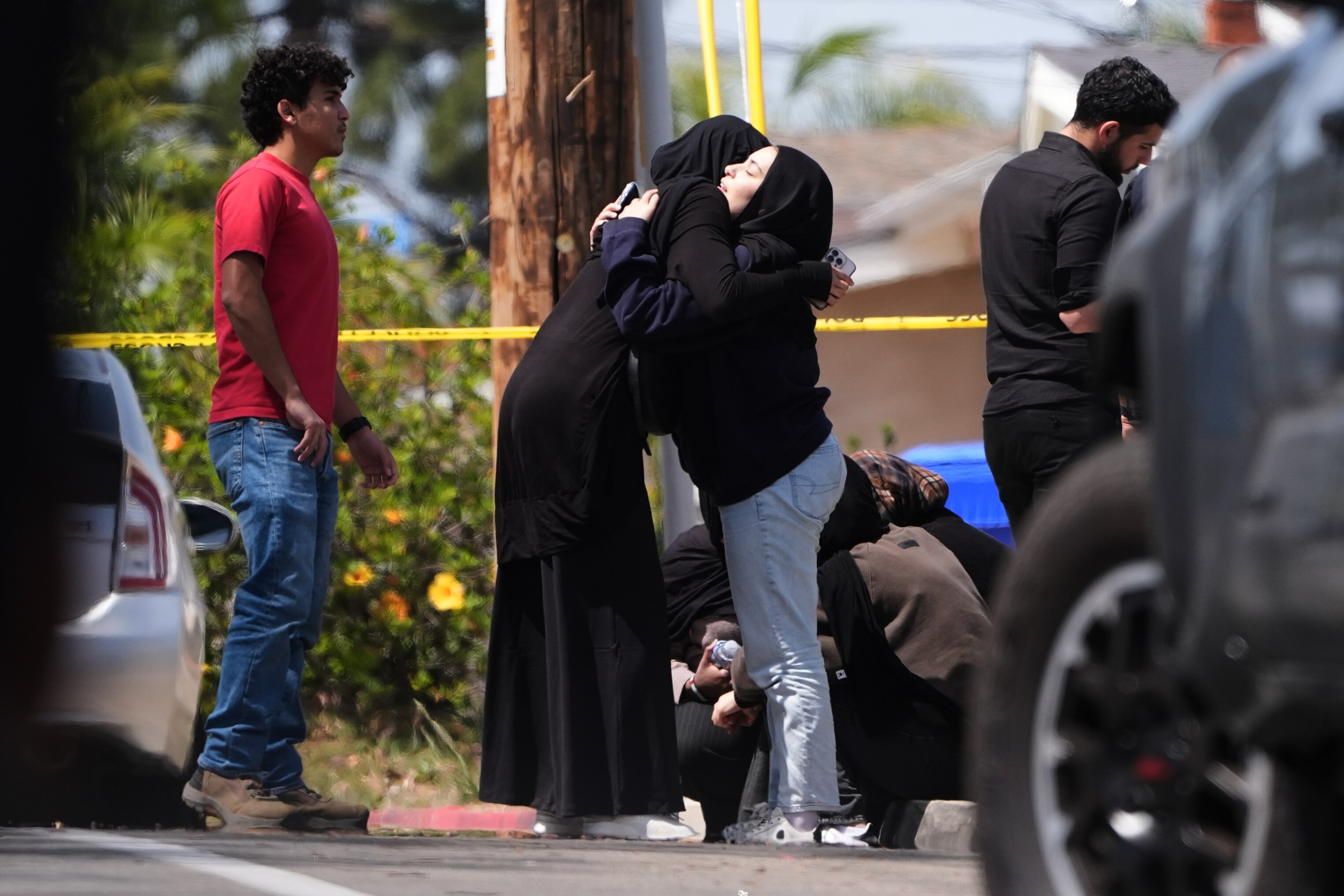 People embrace near the scene of a shooting outside the Islamic Center of San Diego Monday, May 18, 2026, in San Diego.