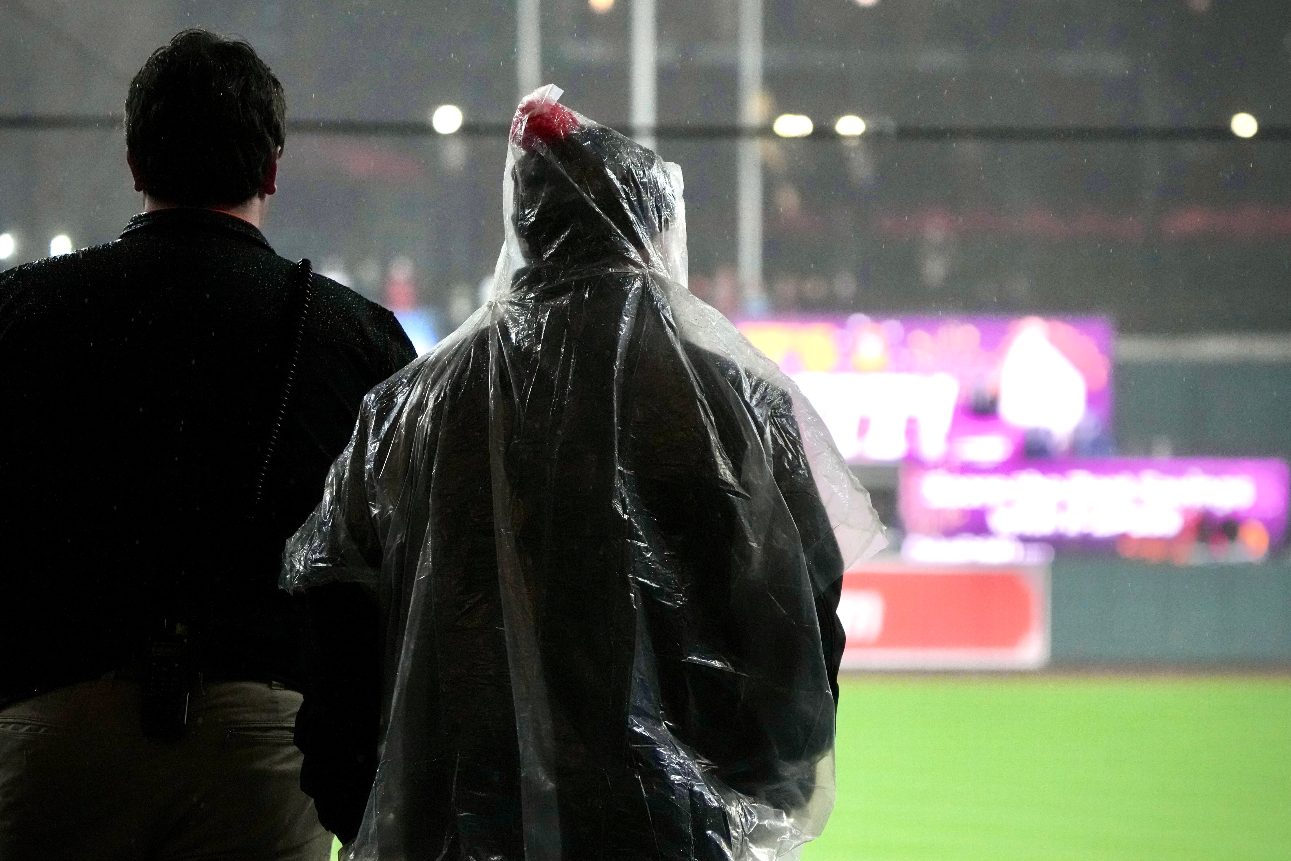 Baltimore Orioles staffers take shelter from the rain during a game against against the Kansas City Royals at Camden Yards on April 2, 2024.