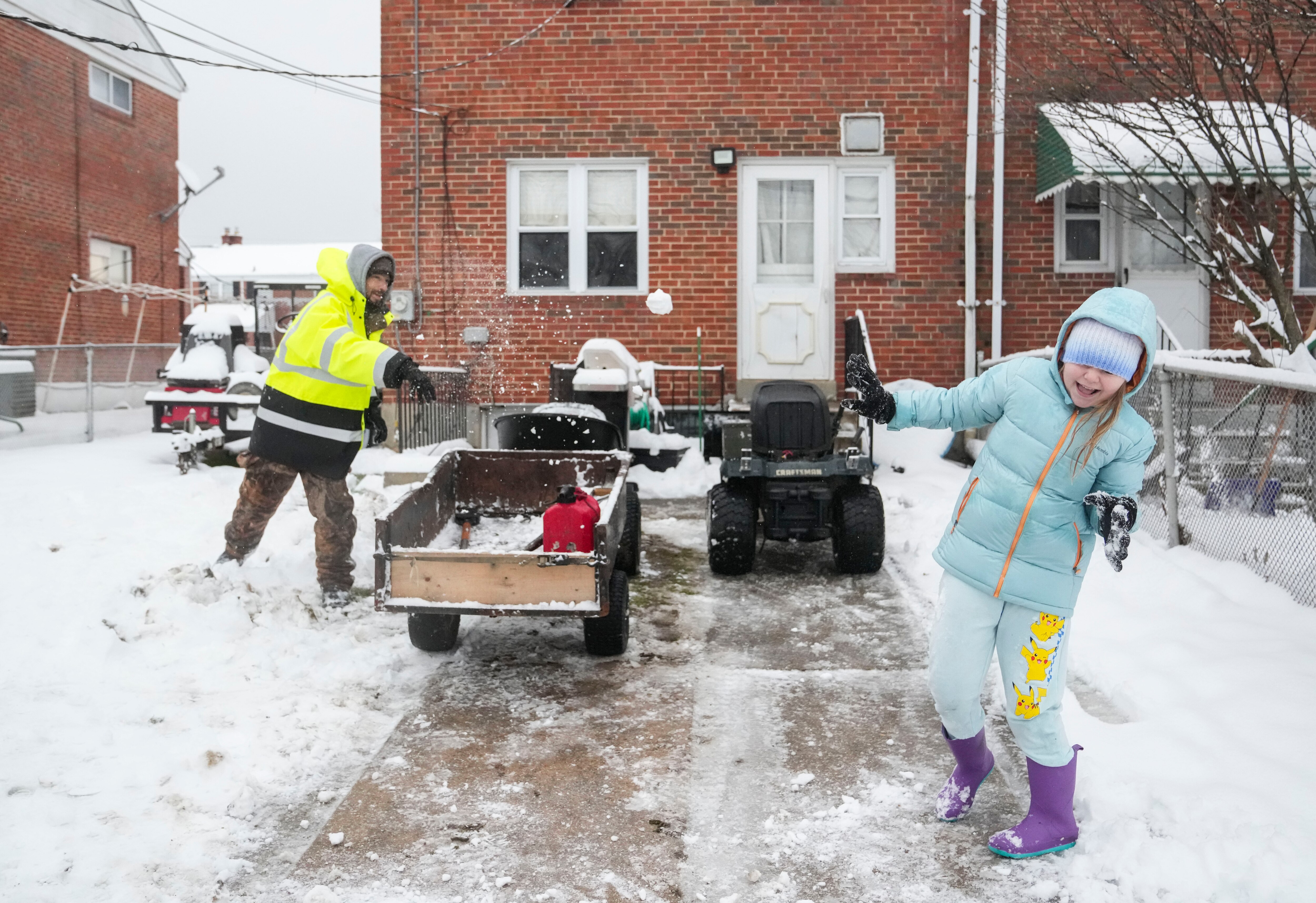 Shawn Newlin throws a snowball at his daughter Hope Newlin, 10, in their backyard, in Dundalk, Maryland, Tuesday, January 16, 2024.