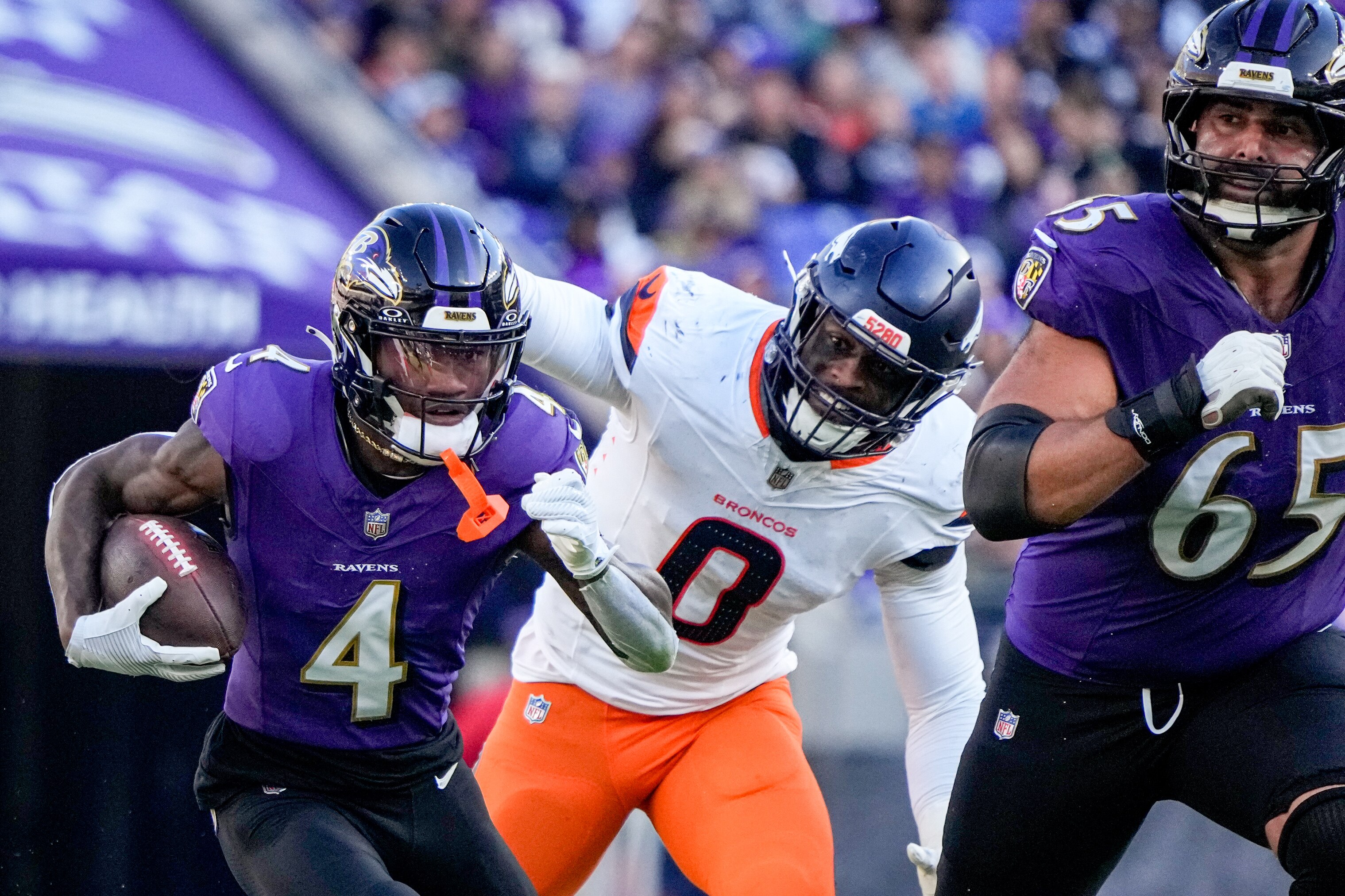 Baltimore Ravens wide receiver Zay Flowers (4) is guarded by guard Patrick Mekari (65) as he tries to outrun Denver Broncos linebacker Jonathon Cooper (0) in a regular season game at M&T Bank Stadium on Sunday, November 3, 2024.