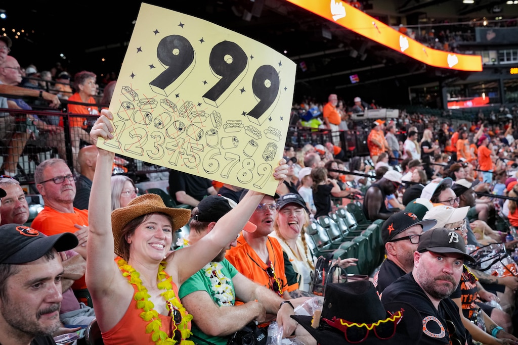 Lauren Carlo holds up a 9 9 9 poster during a baseball game between the Baltimore Orioles and the Cleveland Guardians at Oriole Park at Camden Yards in Baltimore, Md. on Wednesday, September 9, 2026. Carlo along with Casey Jarvis, owner of Glizzy’s Wagyu Dogs, and other friends in their section brought hundreds of hot dogs with them to complete the 9 9 9 challenge during the game Thursday night.