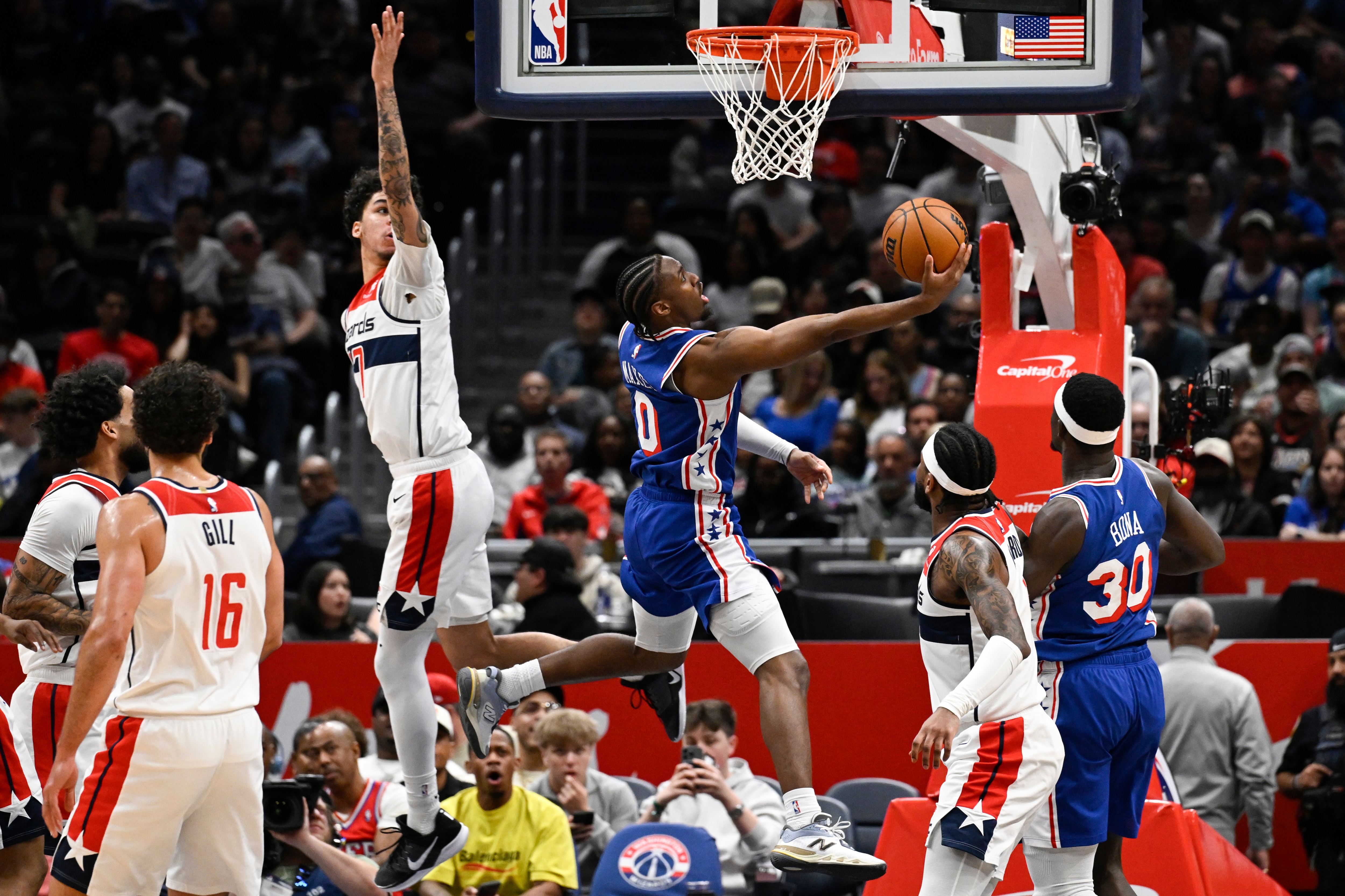 Philadelphia 76ers guard Tyrese Maxey (0) goes to shoot past Washington Wizards guard Will Riley during the first half.