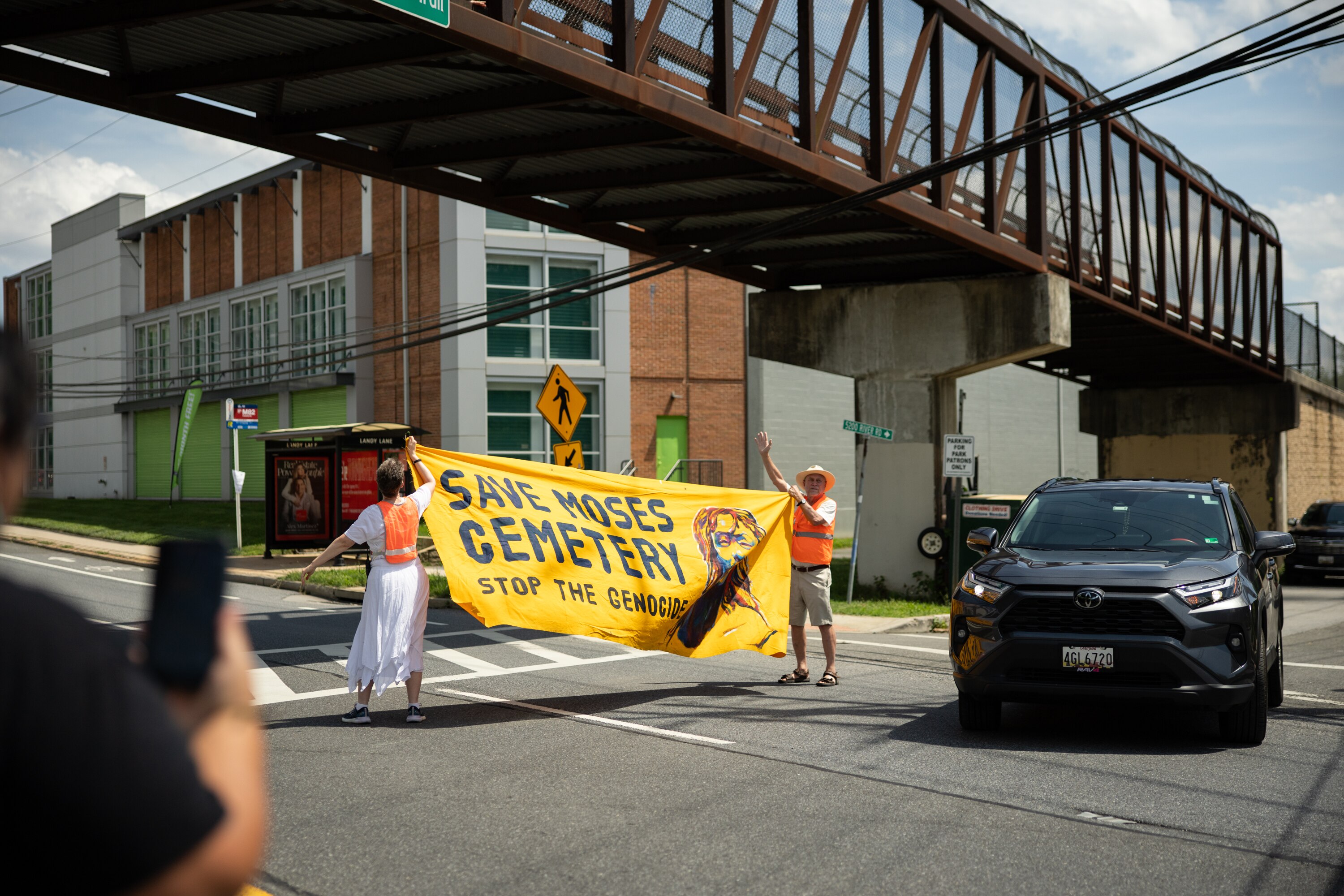 On Thursday, community members lift a sign over a main road in remembrance of a historic Black cemetery buried below the construction of a storage center in Bethesda.