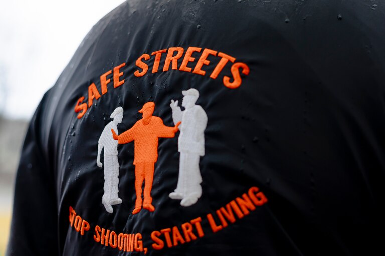 An attendant of an event commemorating a year without homicides wars a Safe Streets jacket, in front of the Safe Streets Penn North site managed by Catholic Charities, on Wednesday, March 6, 2024 in Baltimore, MD.