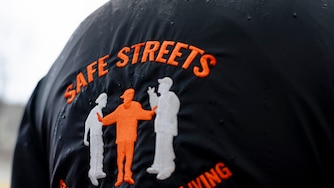 An attendant of an event commemorating a year without homicides wars a Safe Streets jacket, in front of the Safe Streets Penn North site managed by Catholic Charities, on Wednesday, March 6, 2024 in Baltimore, MD.
