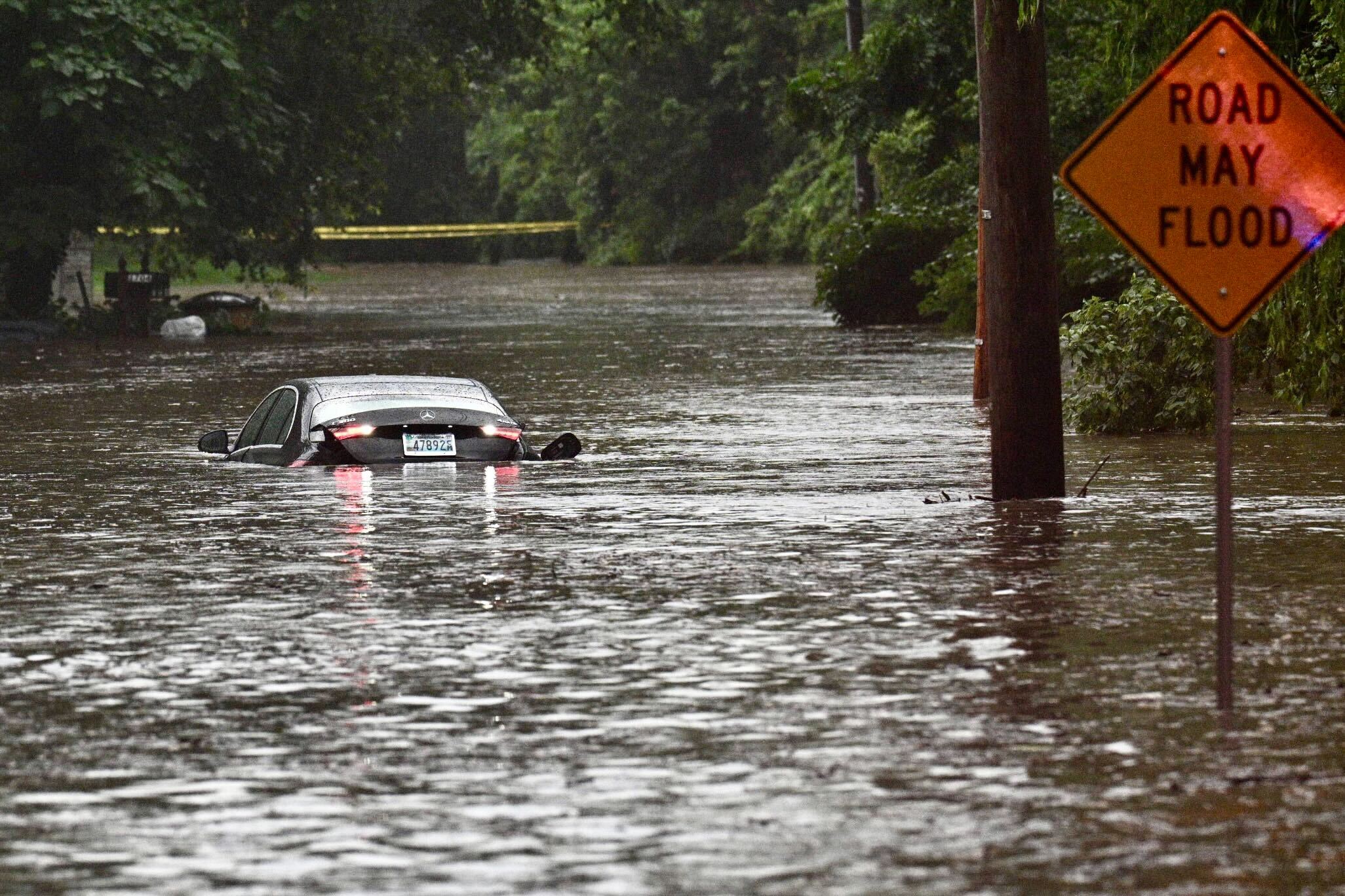 Thursday, July 31, 2025 — A Mercedes sits in floodwater on Ruxton Road where Roland Run spilled over its banks during the afternoon thunderstorms that moved through the region.
