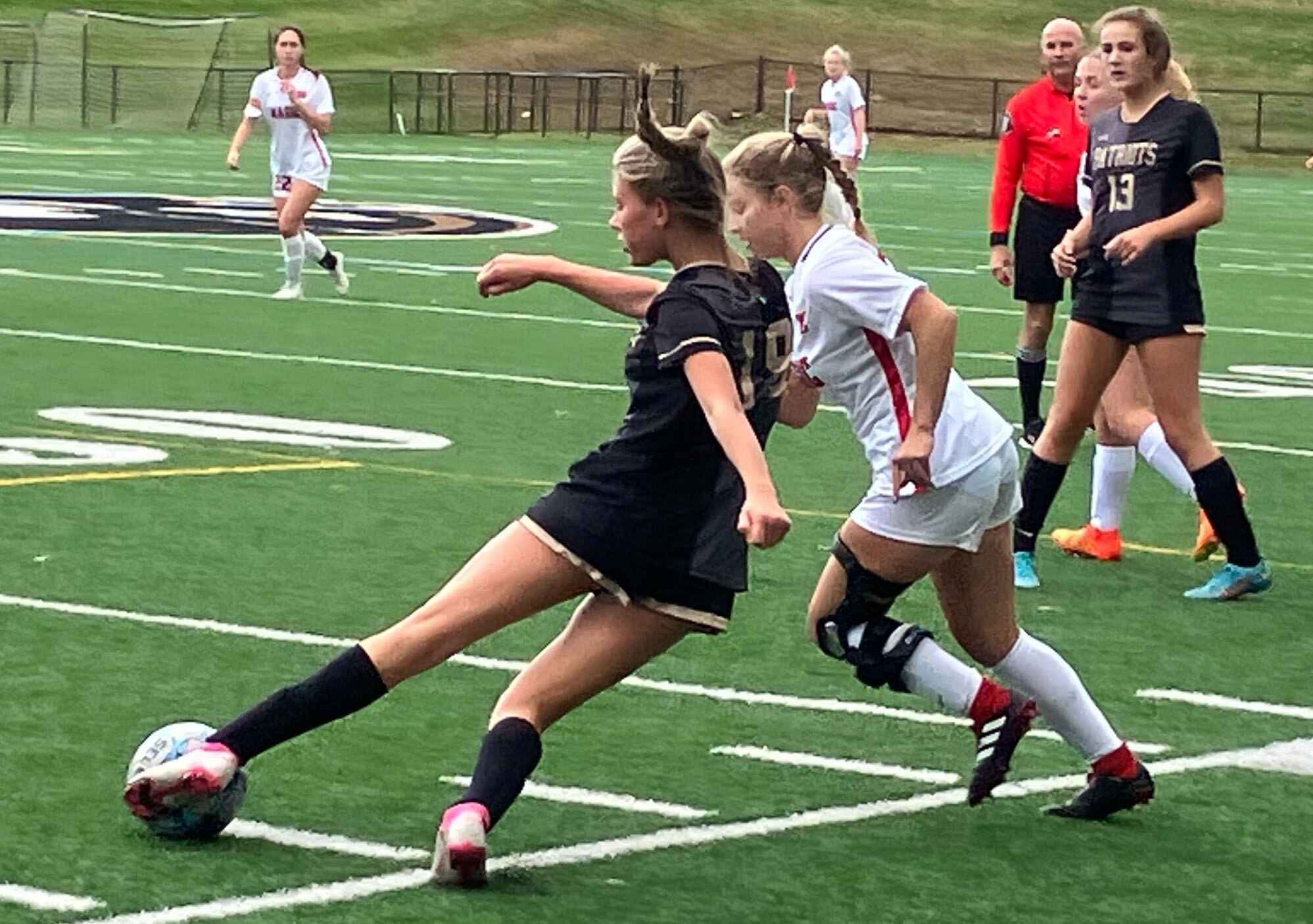 John Carroll junior defender Caroline Harrison attempts to clear the ball while being pressured by Mercy senior forward Brooke Hunter in a showdown for the top seed in the upcoming IAAM A Conference playoffs. The third-ranked Magic toppled the No. 1 Patriots, 2-0, to earn a first-round postseason bye.