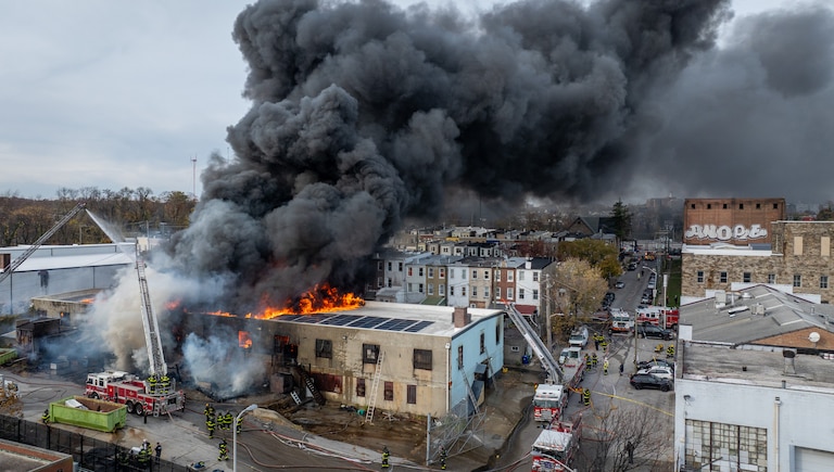 Baltimore Fire crews respond as smoke overtakes a neighborhood from a fire at West 23rd Street and Hampden Avenue in Baltimore on Friday.