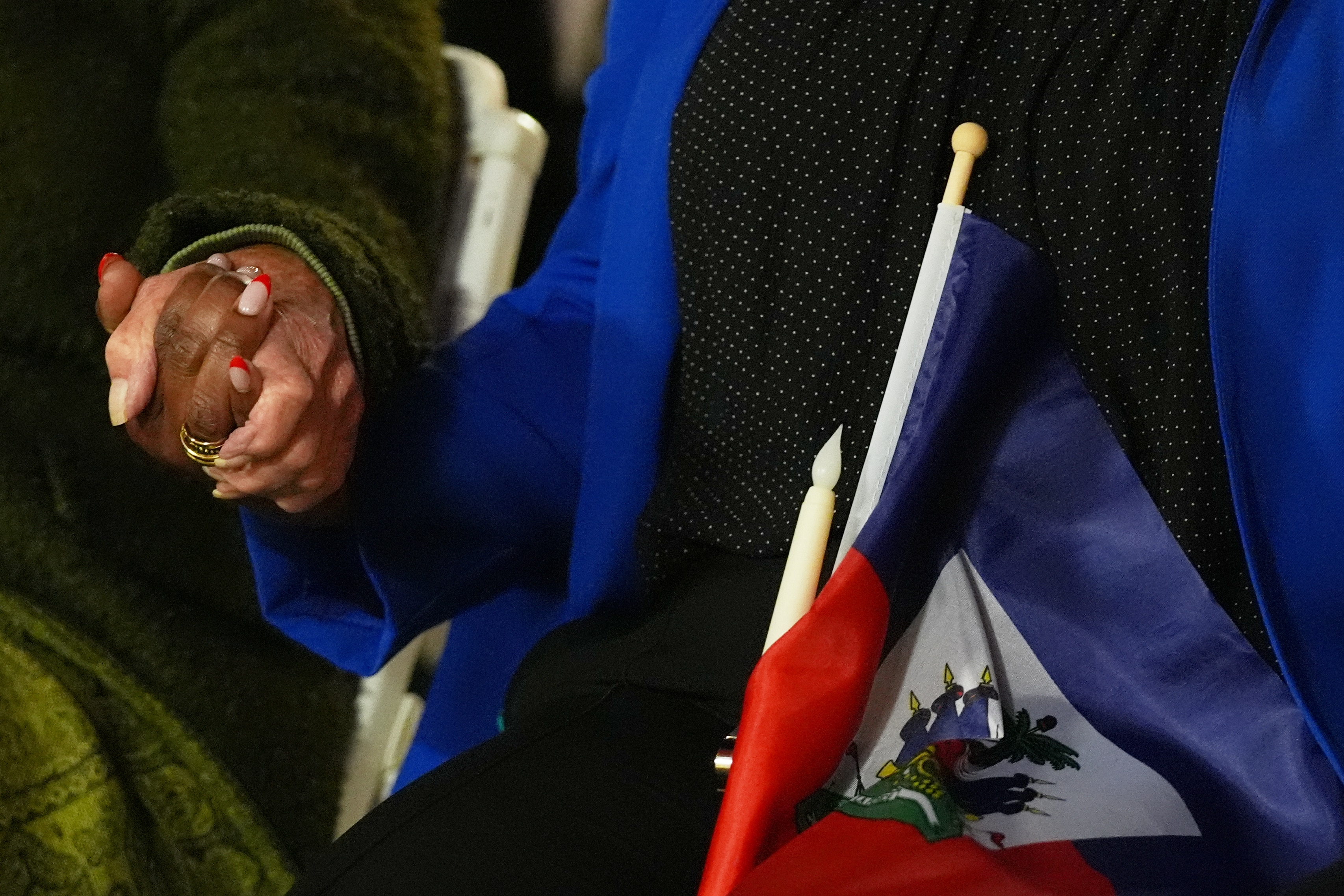 FILE - People hold hands and a Haitian flag during a vigil at the Little Haiti Cultural Complex after a federal judge blocked the Trump administration from ending temporary immigration status, or TPS, for Haitians, Feb. 3, 2026, in North Miami. (AP Photo/Lynne Sladky, File)
