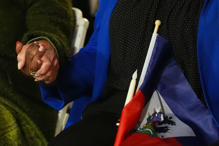 FILE - People hold hands and a Haitian flag during a vigil at the Little Haiti Cultural Complex after a federal judge blocked the Trump administration from ending temporary immigration status, or TPS, for Haitians, Feb. 3, 2026, in North Miami. (AP Photo/Lynne Sladky, File)