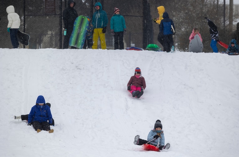 Children sled down a hill on Sunday, Jan. 25, 2026, during a snowstorm in Silver Spring, Md. at Pinecrest Park.