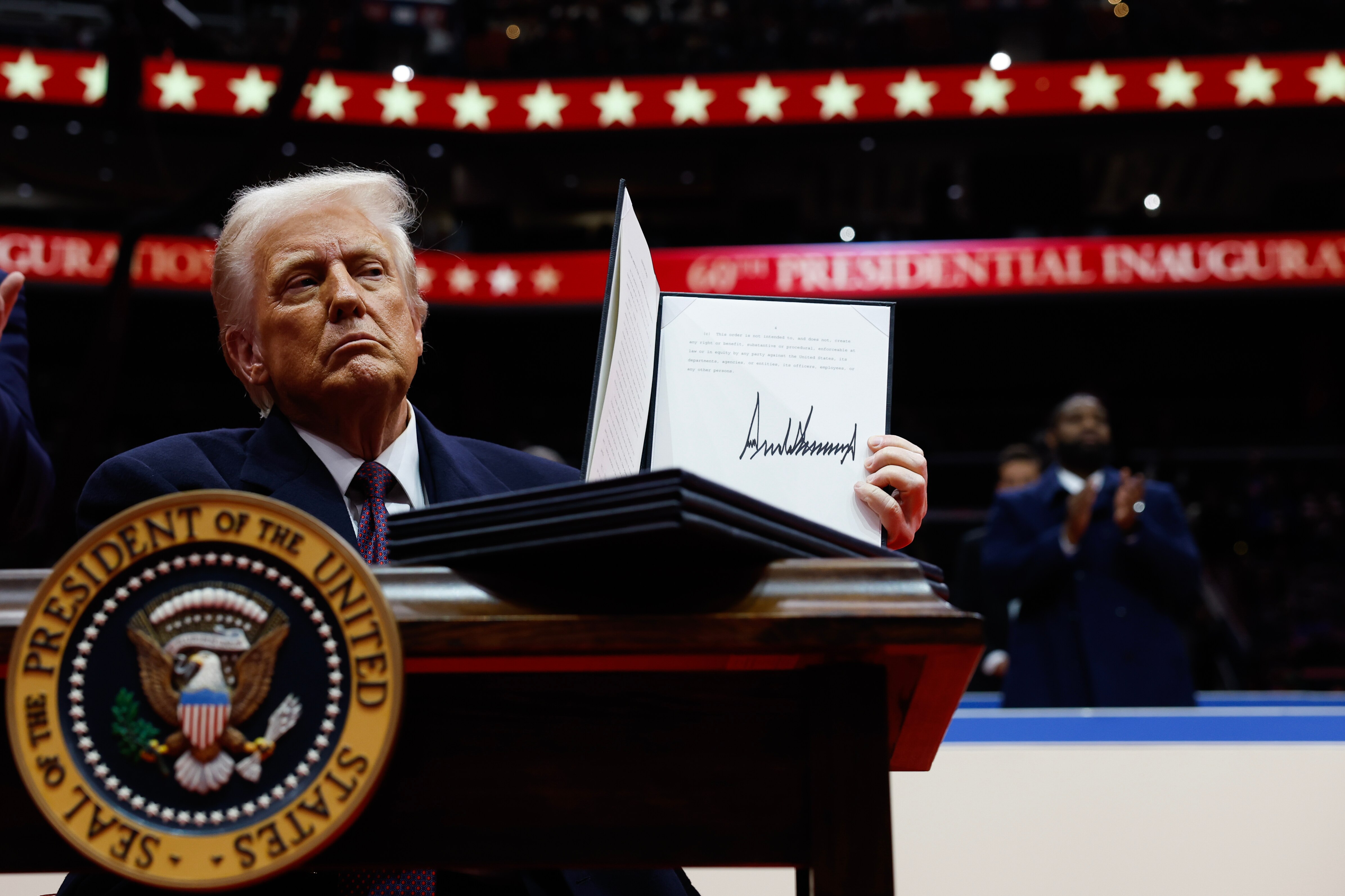 WASHINGTON, DC - JANUARY 20: U.S. President Donald Trump holds up an executive order after signing it during an indoor inauguration parade at Capital One Arena on January 20, 2025 in Washington, DC. Donald Trump takes office for his second term as the 47th president of the United States.