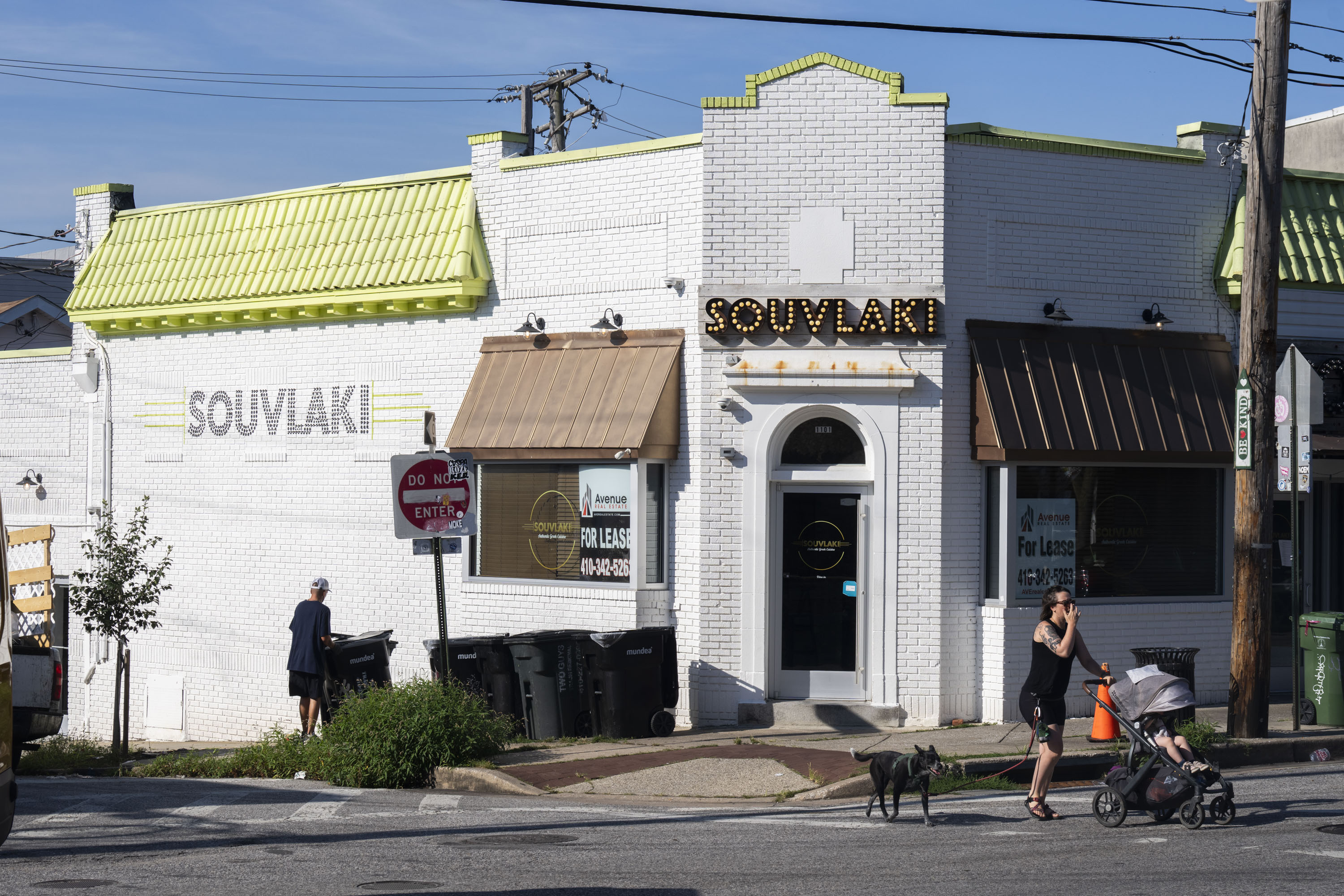 A man collects trash in front of the now closed Greek cuisine restaurant, Souvlaki, on July 28, 2025.