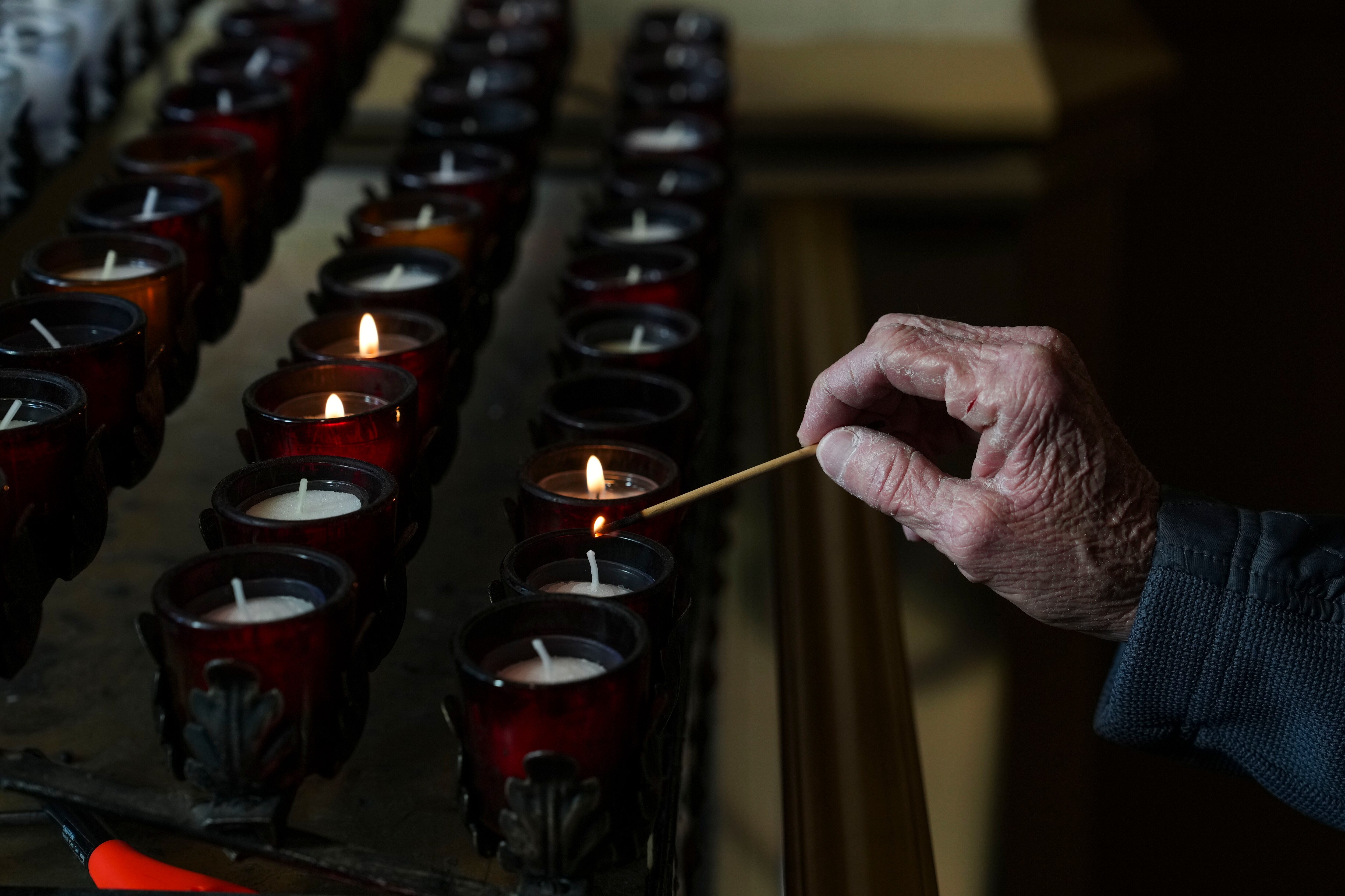 Liz Murphy and Linda Malat Tiburzi say a prayer and light candles in honor of their friend and former classmate Eddie Blair