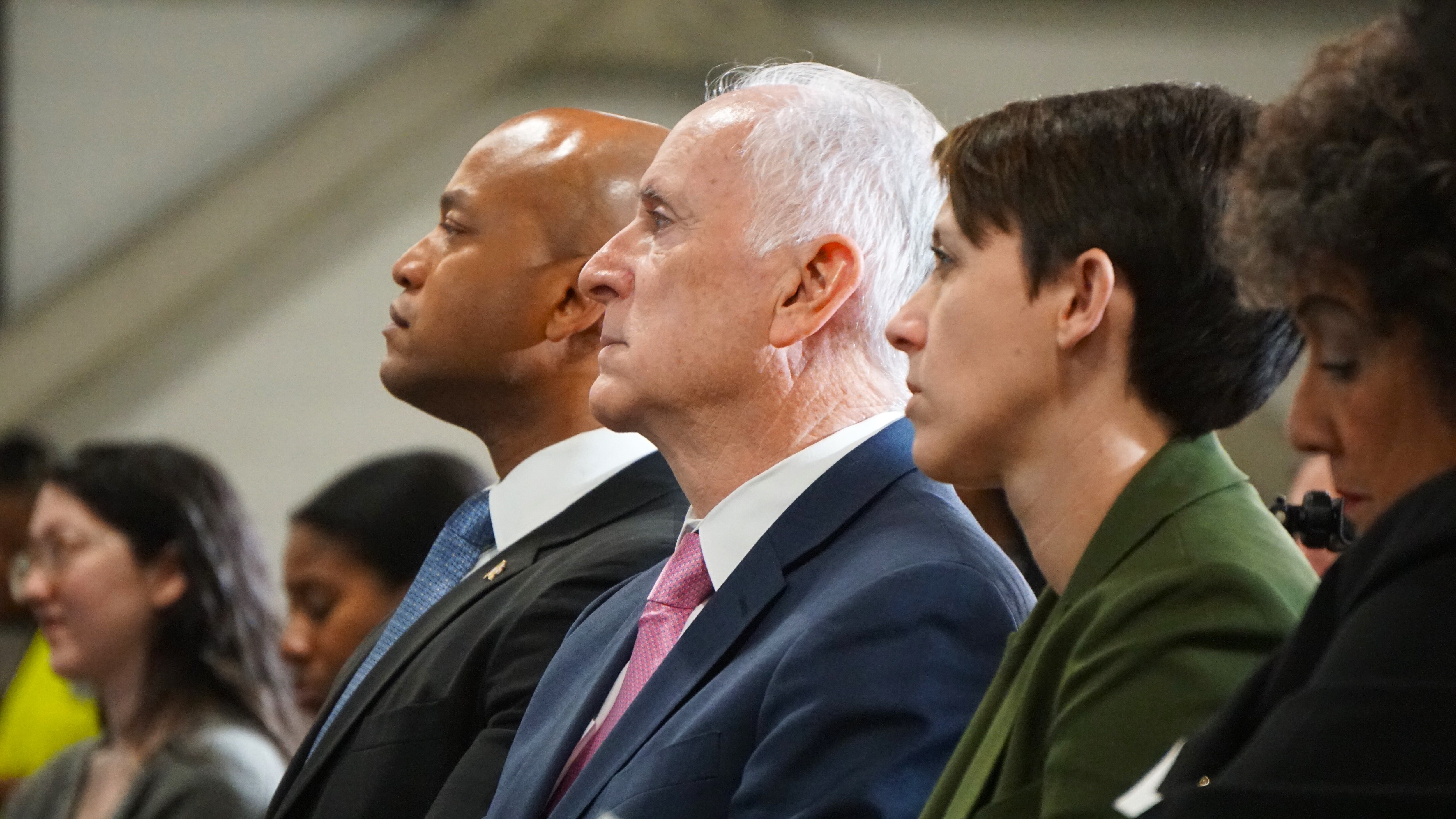 A profile image of two men and one woman sitting in a line looking to the left side of the frame.