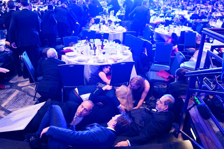 Attendees hide under tables after an incident at the annual White House Correspondents Association Dinner April 25, 2026 in Washington, DC. According to reports, President Donald Trump, along with other government officials, were evacuated from the Washington Hilton after what sounded like gun fire.