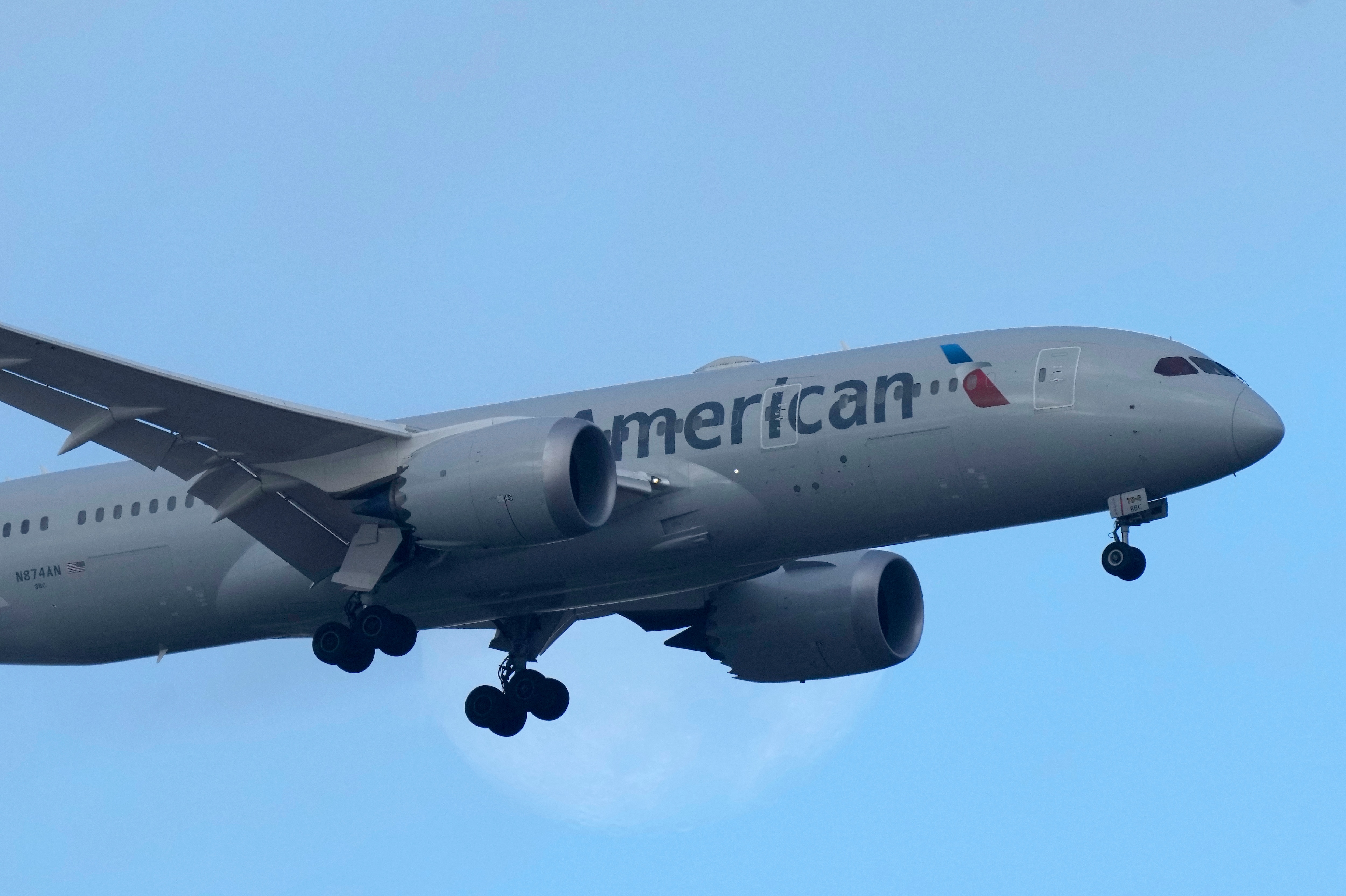 An American Airlines Boeing 787 approaches for landing in Lisbon, with the setting moon in the background, Saturday, Sept. 2, 2023.