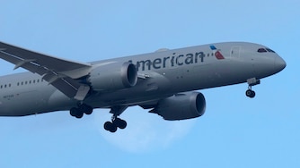 An American Airlines Boeing 787 approaches for landing in Lisbon, with the setting moon in the background, Saturday, Sept. 2, 2023.
