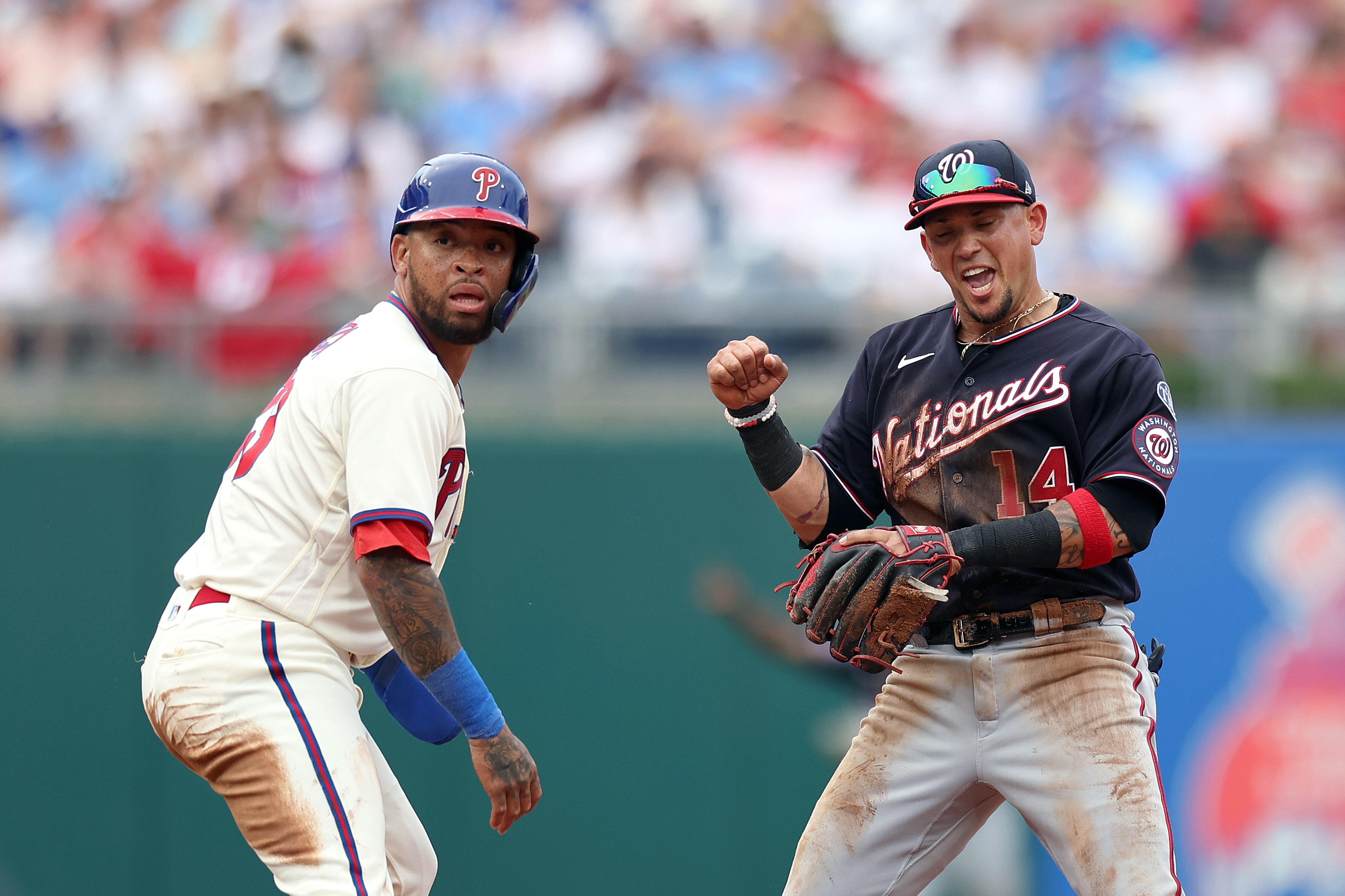 Nationals infielder Ildemaro Vargas and Phillies runner Edmundo Sosa react differently after watching the completion of a play at first base.