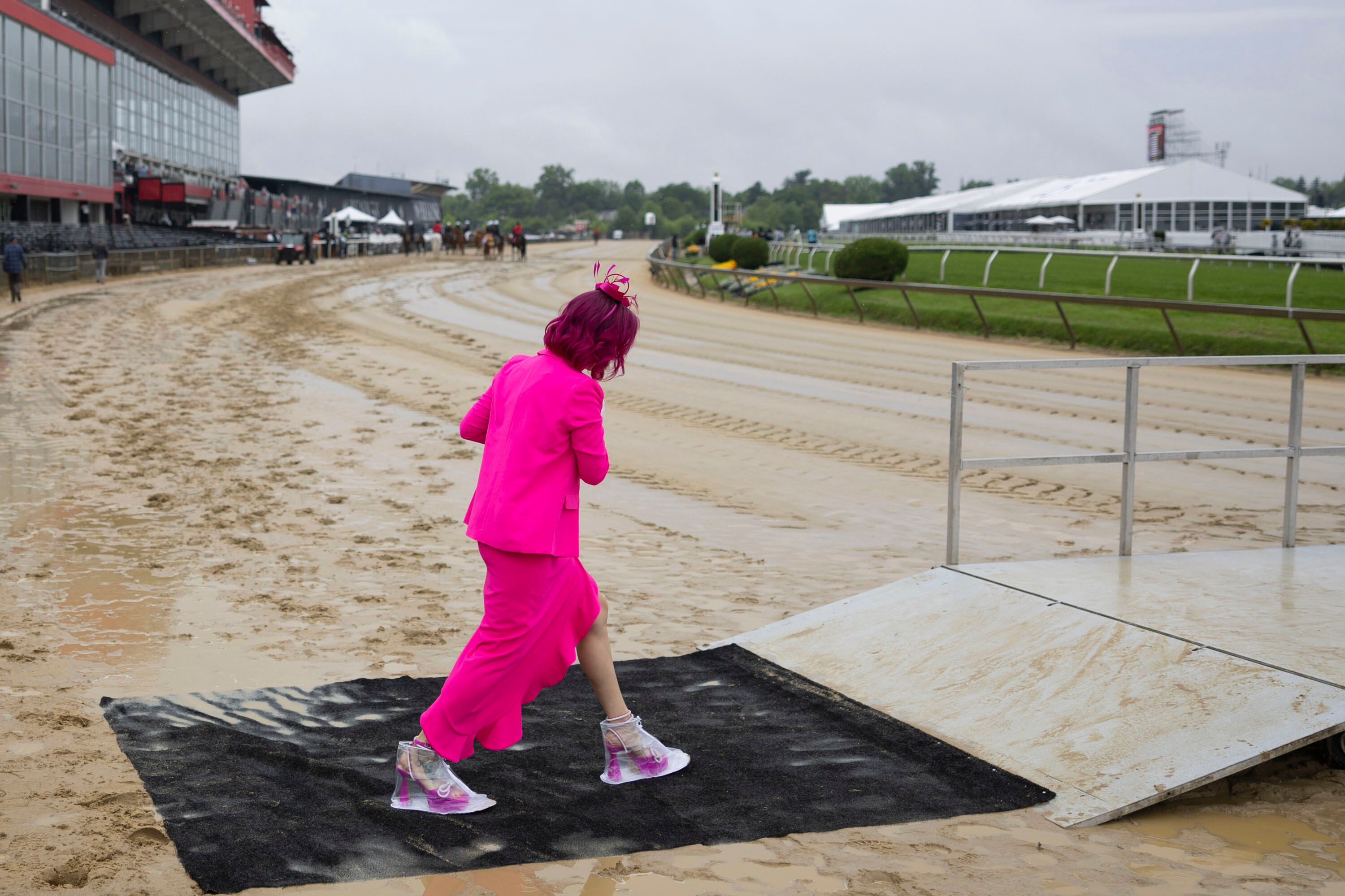 An attendee crosses a muddy track ahead of the first race of the day Saturday at Pimlico Race Course.