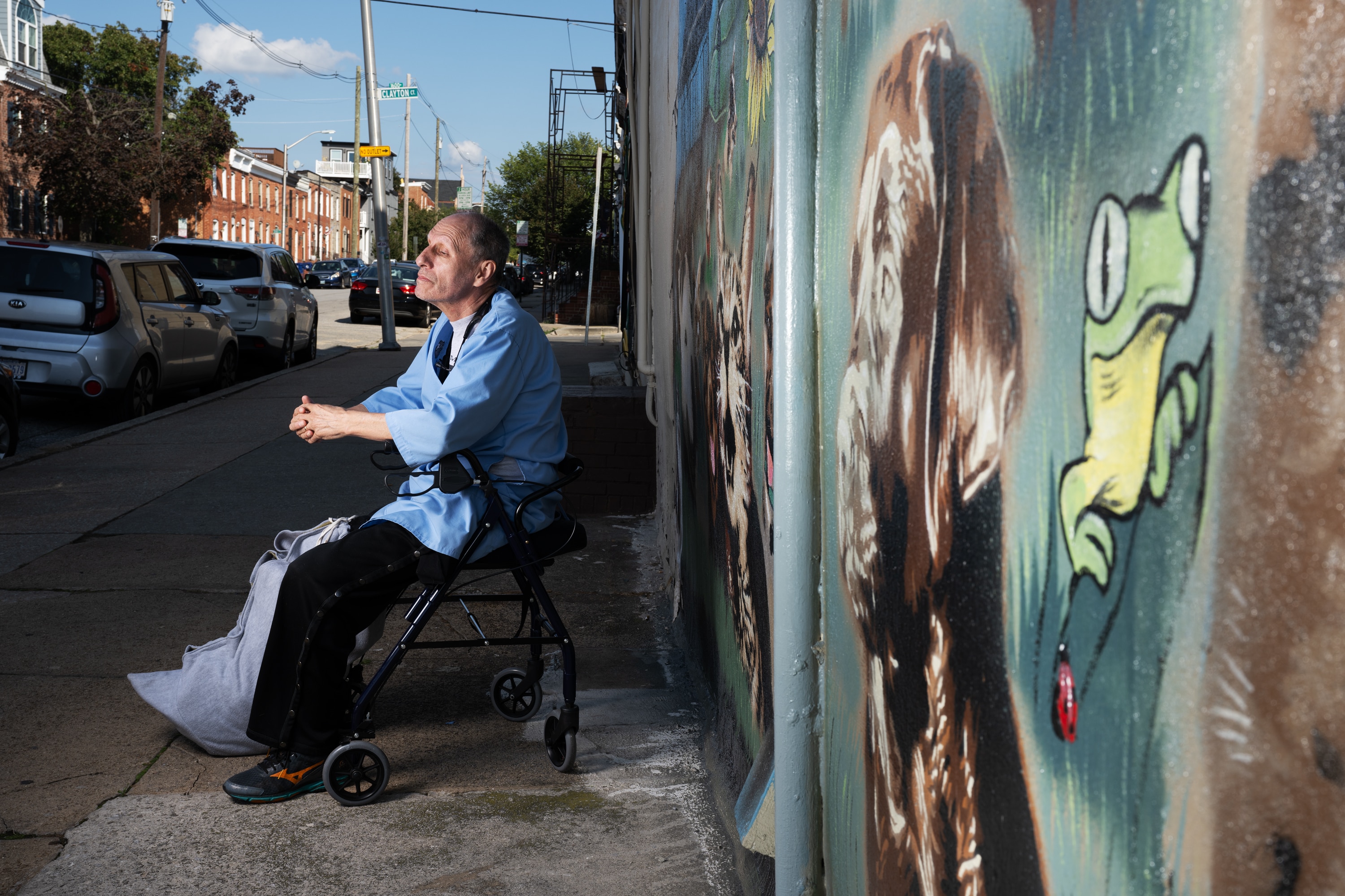 Dr. John Trujillo, 67, of Harford County, a veterinarian who opened what’s now called Pickles Light Street Animal Hospital more than 20 years ago in Baltimore, poses for a portrait in front of a large mural made on the side of the medical facility on Monday, Sept. 18, 2023. The frog is painted in memory of his son, John Jr., who died in 2017. Trujillo is continuing to recover more than one year after his younger brother, Bobby, shot him in the right leg on Aug. 29, 2022.