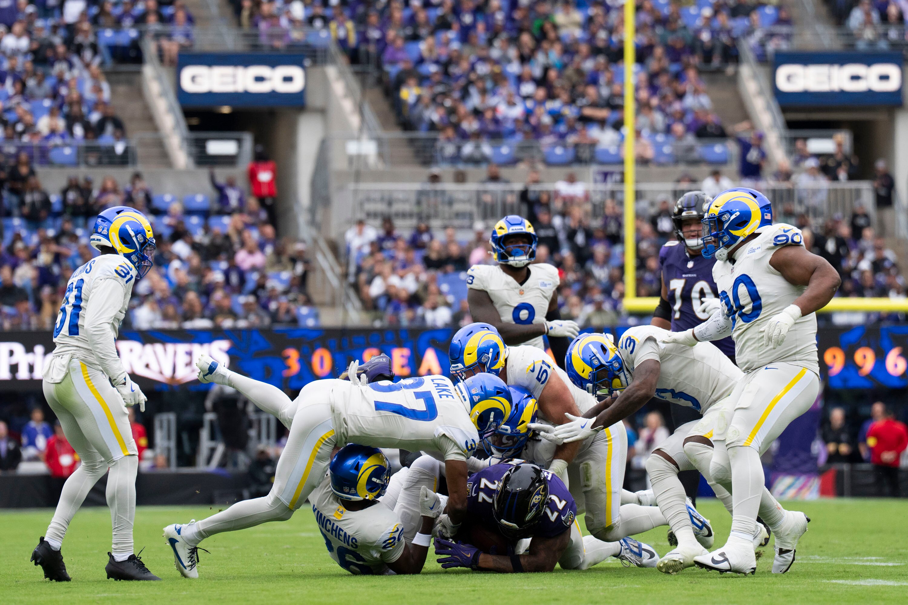 Rams Safety Quentin Lake, bottom left,  tackles Ravens running back Derrick Henry, center, during the first quarter of the Ravens vs Rams football game at M&T Bank Stadium on October 12, 2025.
