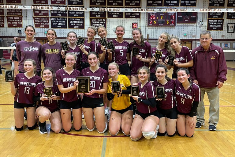 The Hereford volleyball team gathers for a team photo with Baltimore County championship plaques following their three set victory over Perry Hall, Tuesday in Parkton.