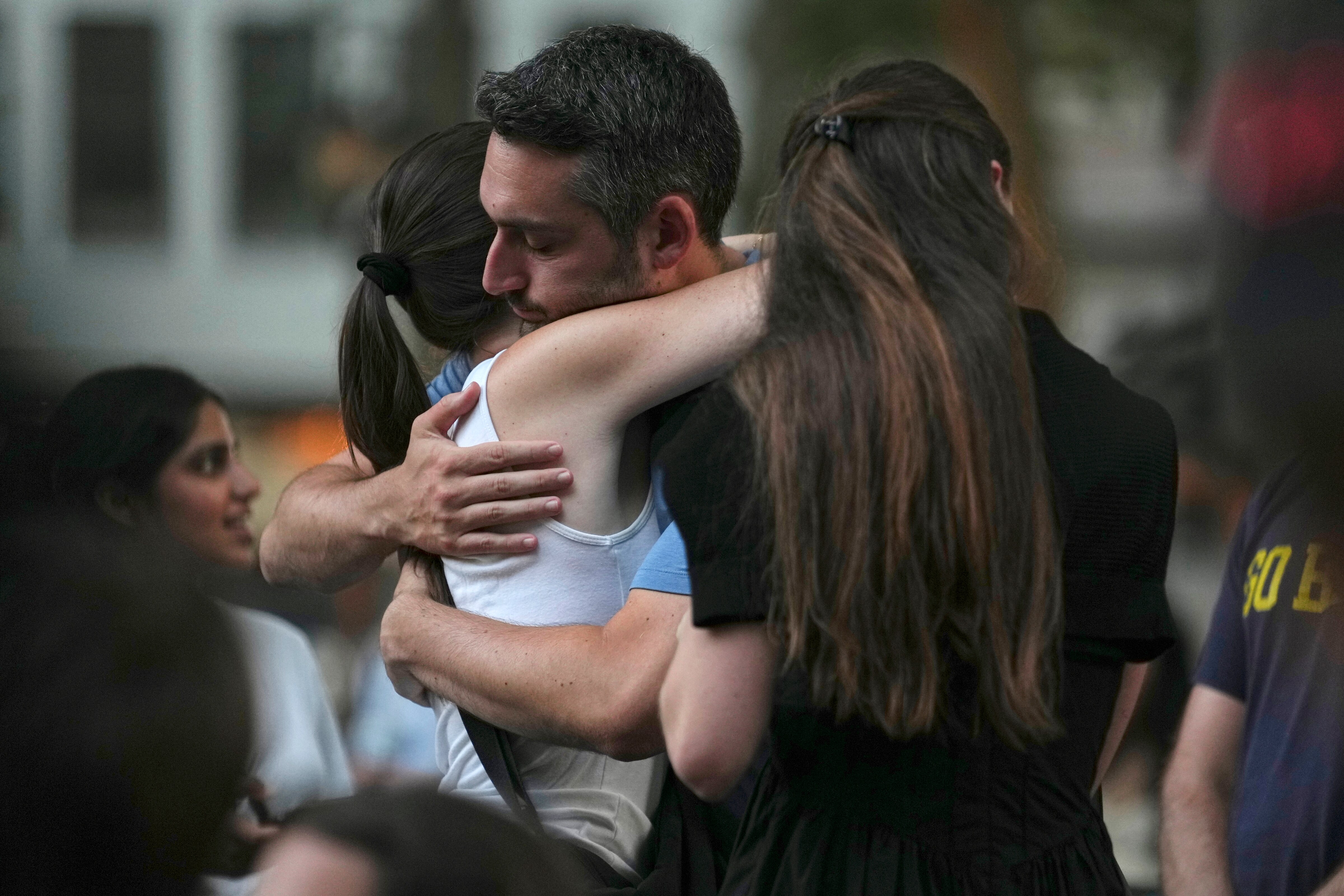 People hug while attending a vigil at Bryant Park for the people killed by a gunman at a Manhattan office building the day before, Tuesday, July 29, 2025, in New York.