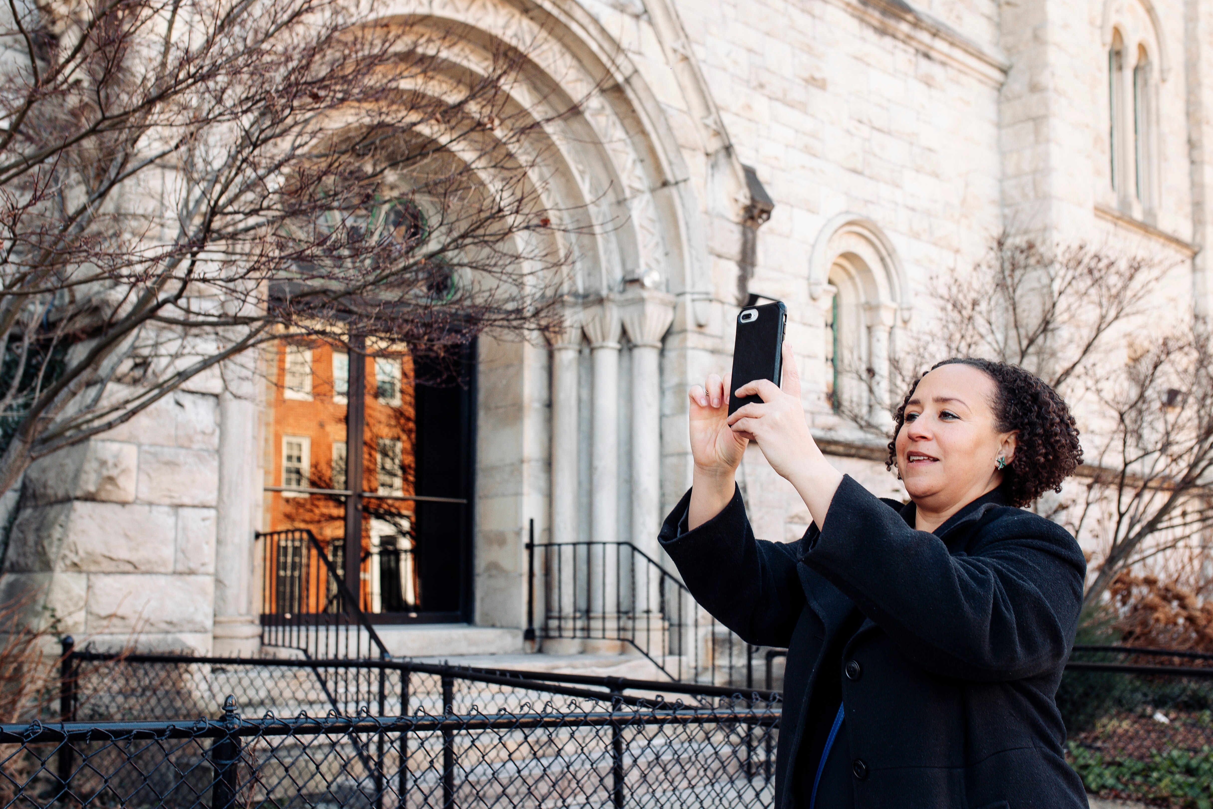 Filmmaker Taura Musgrove uses her phone to view the augmented reality history lessons she created about Dr. Lillie May Carroll Jackson and the Bethel A.M.E. Church, where Jackson used to host the Baltimore Young People's Forum, on Wednesday, Feb. 21, 2024 in Baltimore.