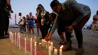 People light candles during a prayer vigil for the victims of a mass shooting earlier in the day, Sunday, April 19, 2026, in Shreveport, La.
