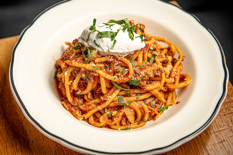 Caruso's Grocery serves up a rich, spicy ragu sauce over bucatini, topped with a dollop of fresh ricotta.