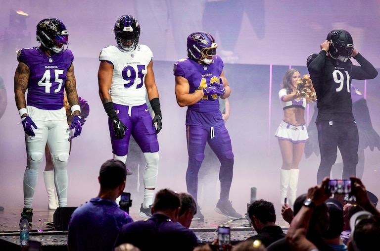 Ravens players Mike Green, Tavius Robinson, Justice Hill, and Trey Hendrickson model the four newly designed uniform styles on stage during an event at Merriweather Post Pavilion on Thursday.