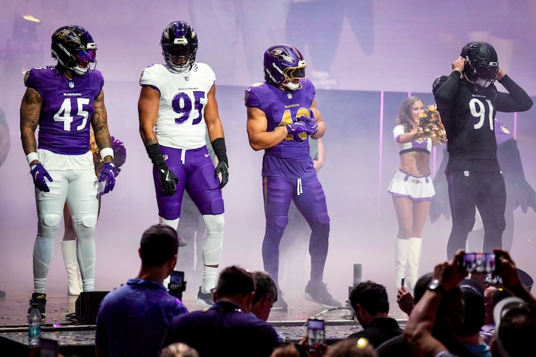 Ravens players Mike Green, Tavius Robinson, Justice Hill, and Trey Hendrickson model the four newly designed uniform styles on stage during an event at Merriweather Post Pavilion on Thursday.