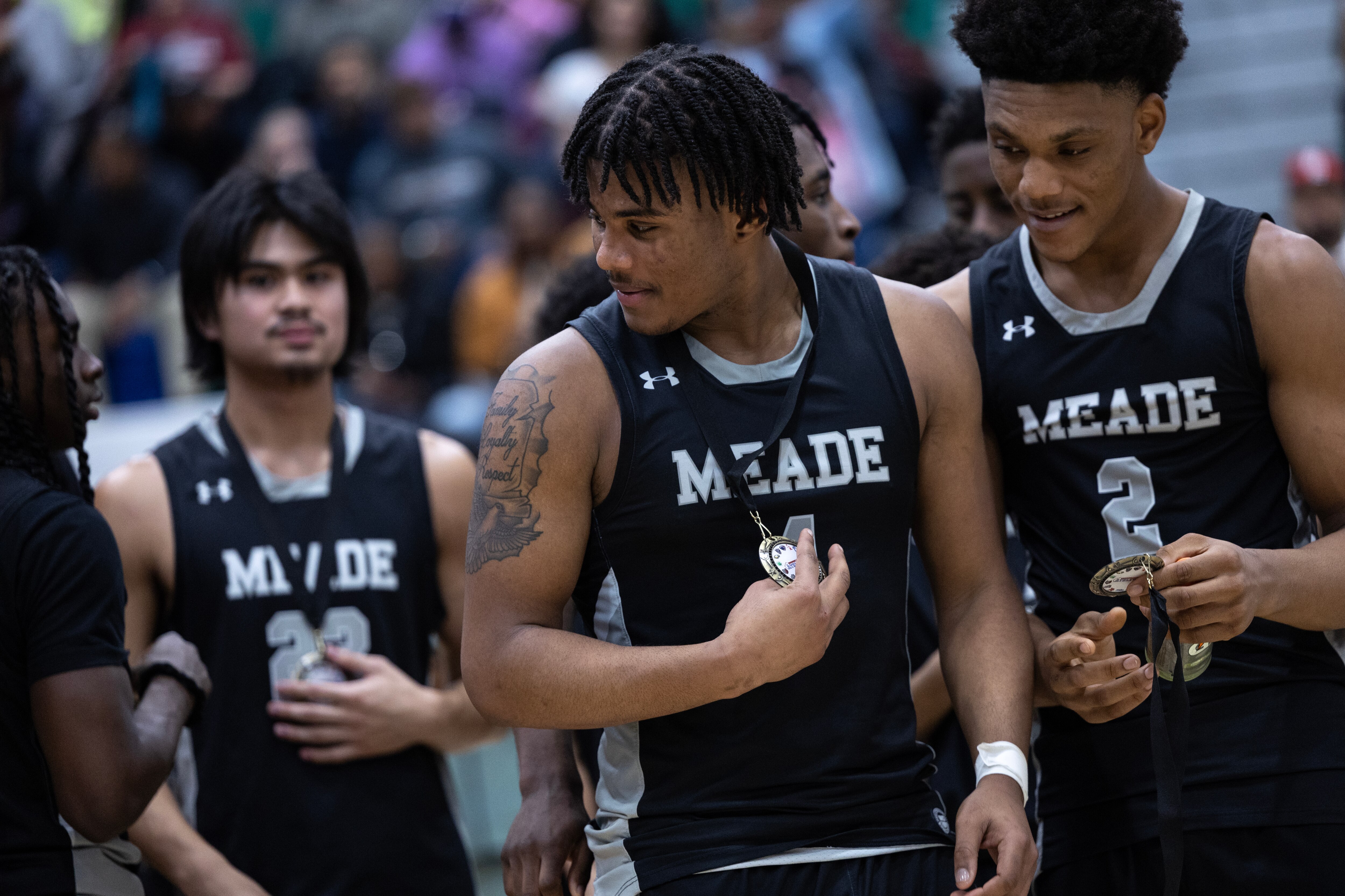 Meade players examine their medals following their victory in the Anne Arundel County Boys Basketball Championship game in Odenton, Md., on Saturday, February 18, 2023.  Meade defeated Broadneck 60-51 in regulation time to win the championship.