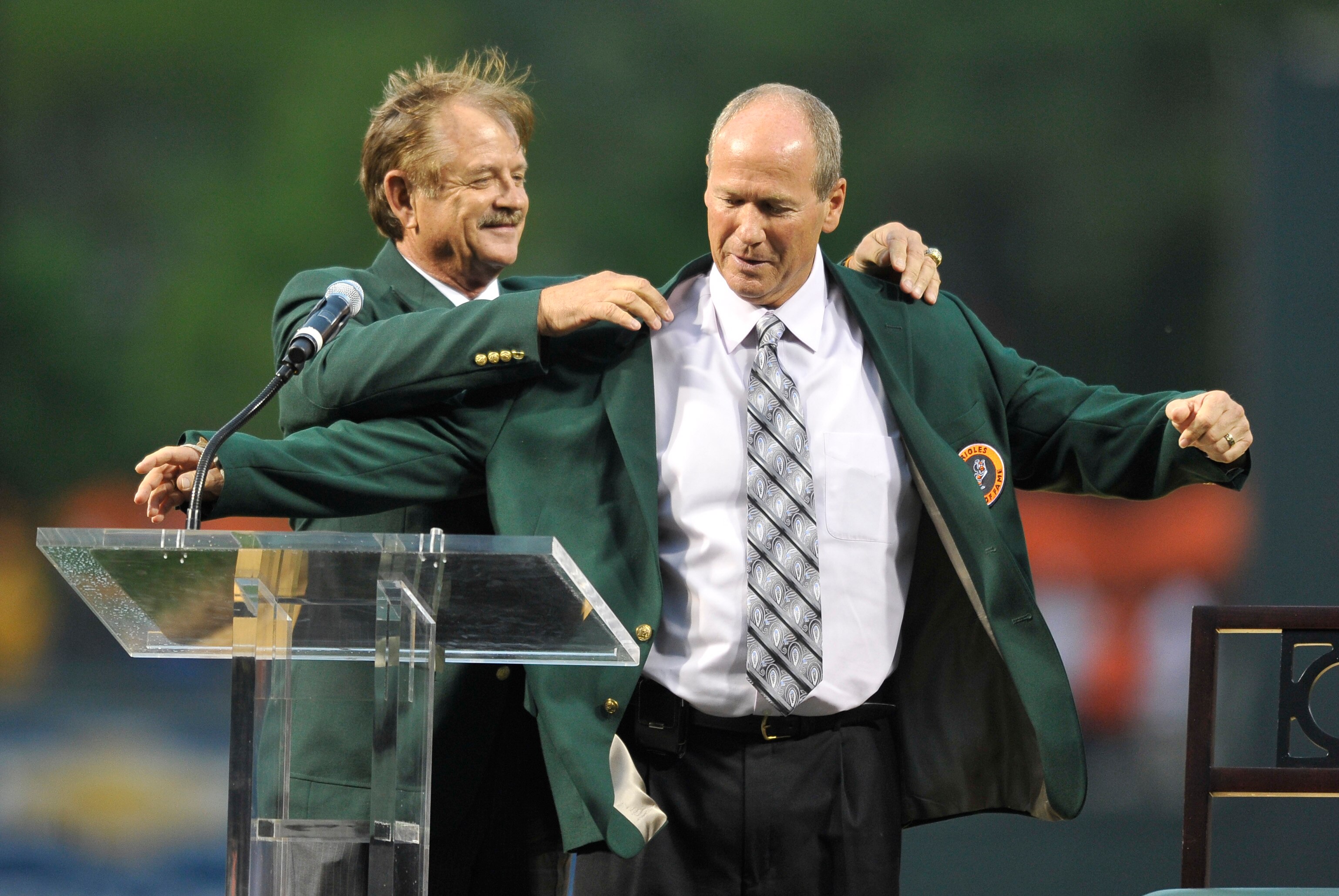 Former Baltimore Orioles catcher Rick Dempsey, left, helps former Orioles player Rich Dauer put on an Orioles Hall of Fame jacket in 2012.