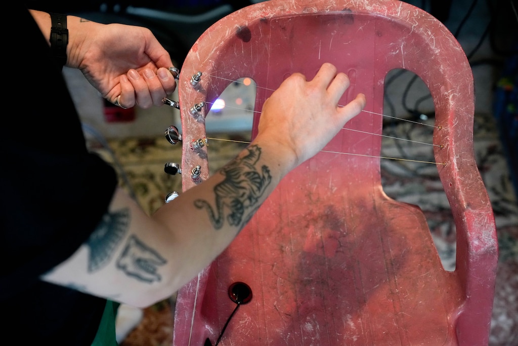 Dan Ortiz Leizman, an artist and lecturer at the University of Maryland, College Park, tunes a Monobloc Chair Harp that they created in their home in Hyattsville, Md. on Wednesday, June 10, 2026.