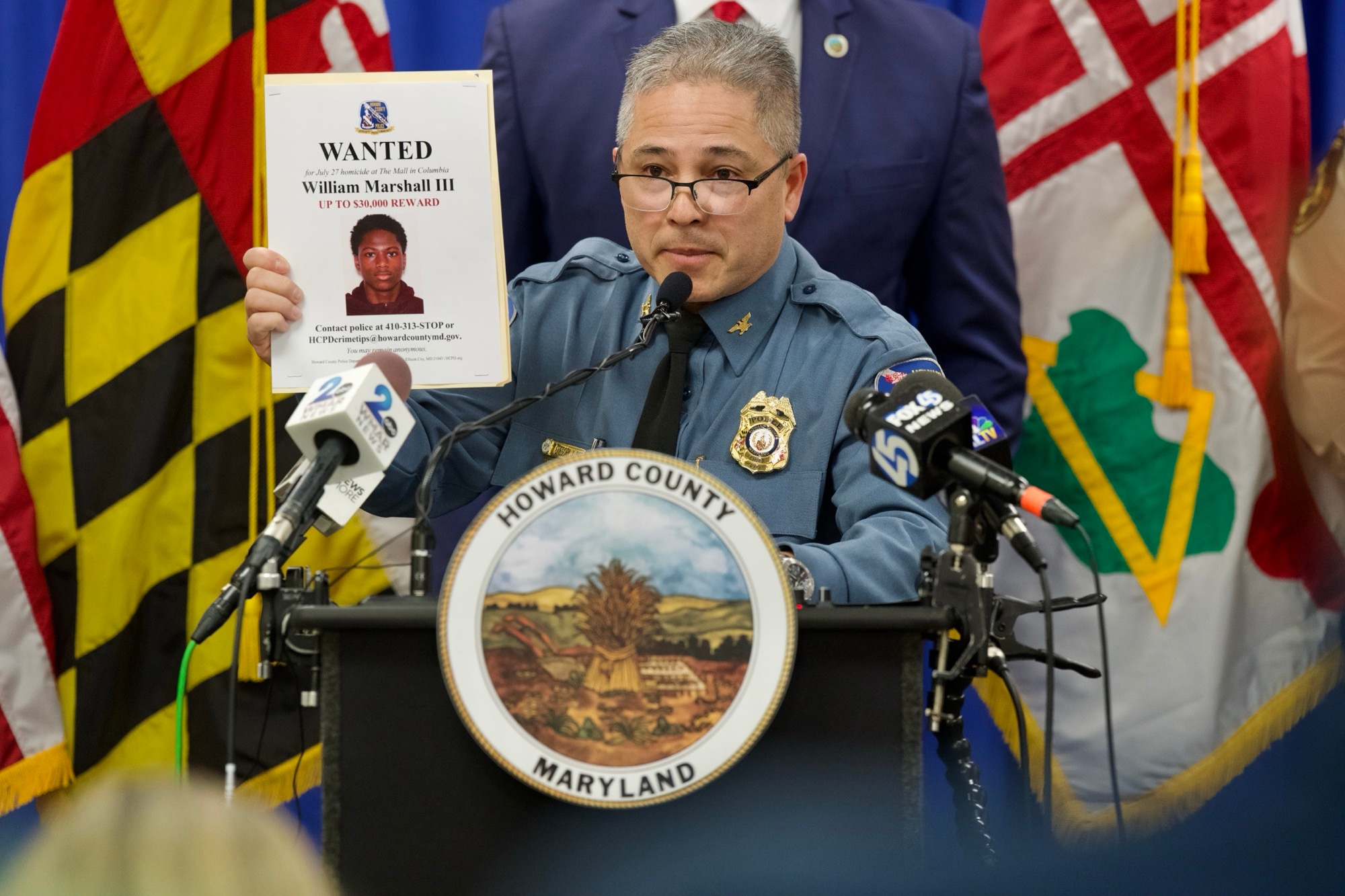 Gregory Der, Howard County Police Chief, holds up a photo of a suspect wanted in the 2024 Columbia Mall shooting during a press conference where he discusses recent crime on February 27, 2025.