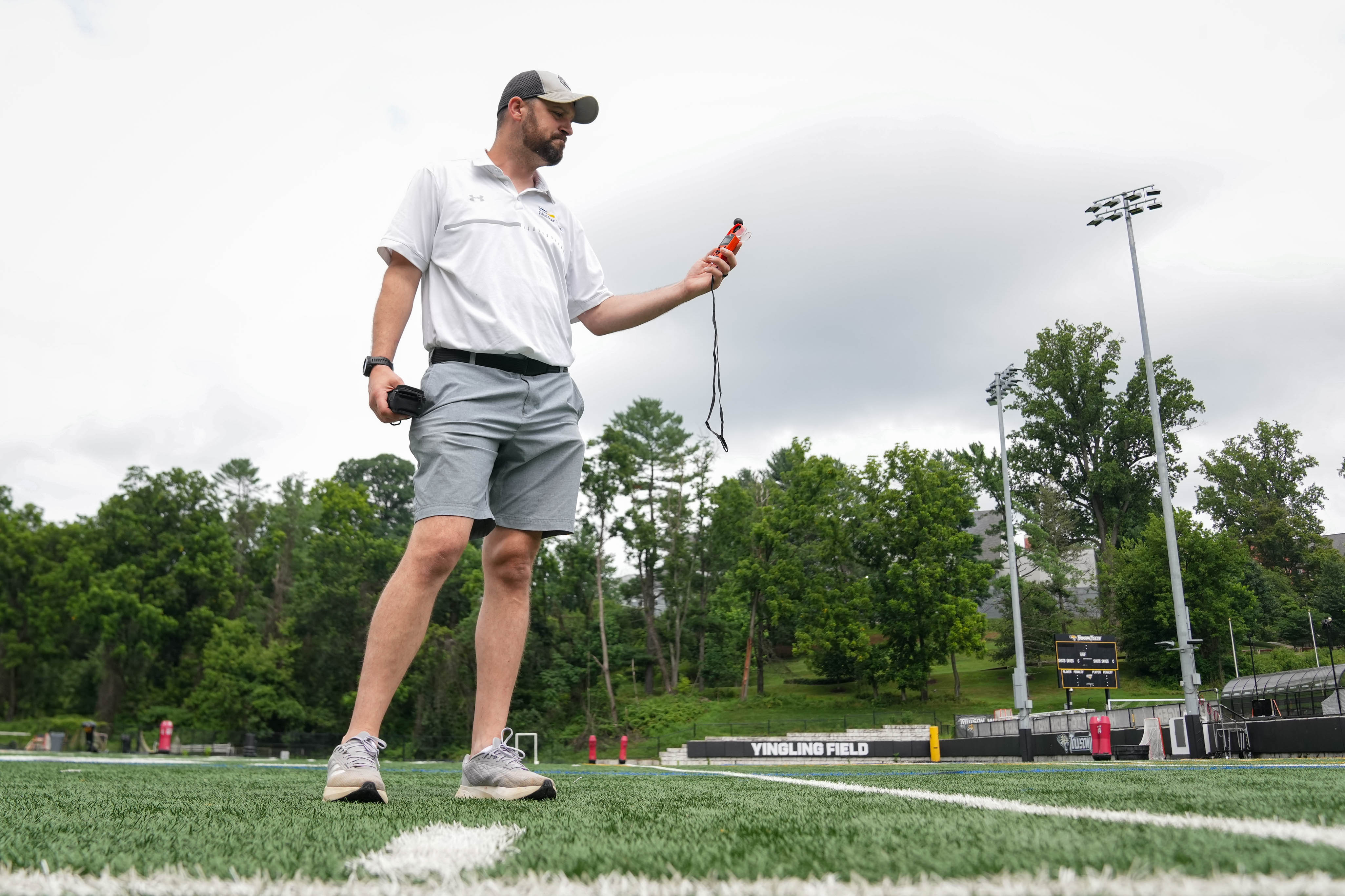 Tim Happel, head athletic trainer with Medstar Health, examines a reading on the Kestrel heat stress tracker on the Yingling practice field at Towson University in Towson, Md. on Tuesday, July 15, 2025.
