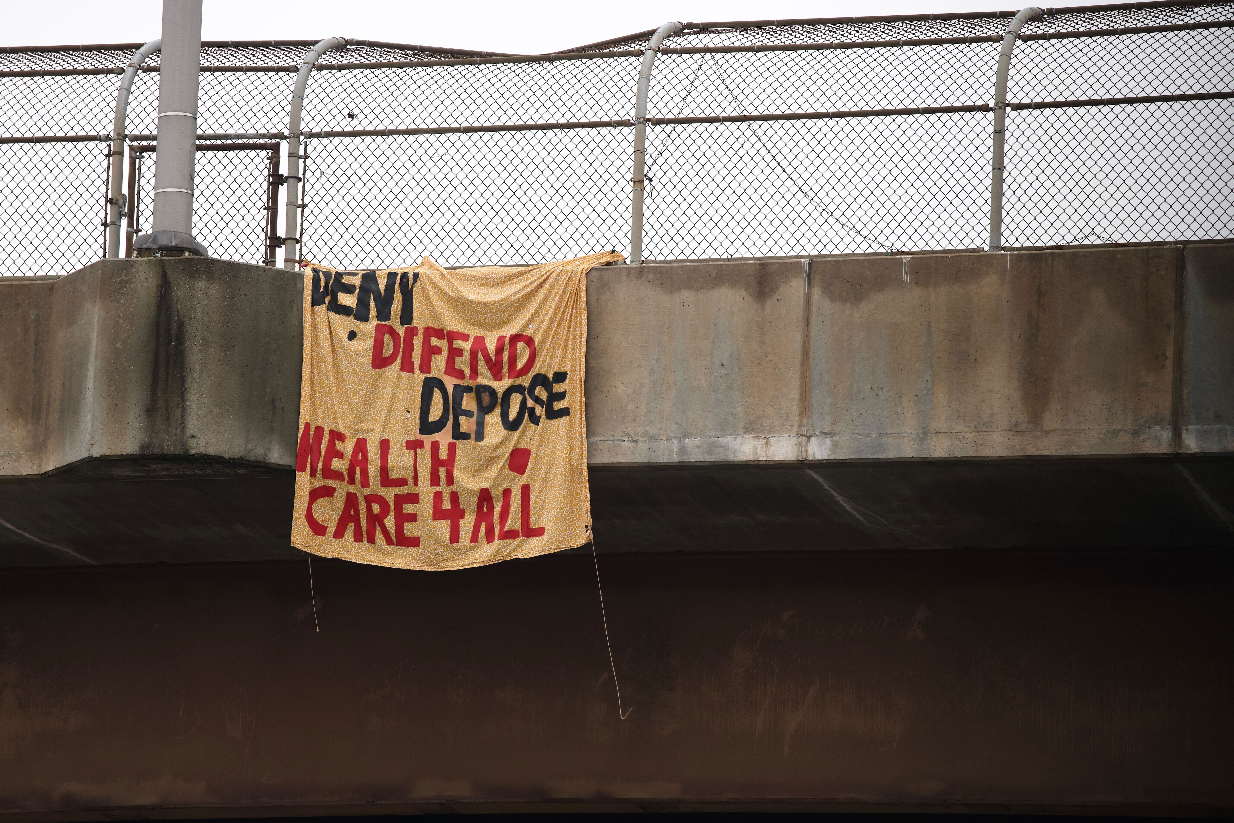 A sign reading "Deny, Defend, Depose, Health Care 4 All" hangs on an overpass on I-83 on Tuesday, Dec. 10, 2024.