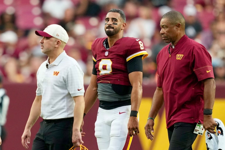 Washington Commanders quarterback Marcus Mariota (8) walks off the field with training staff after appearing to suffer an injury during a handoff in the first quarter.