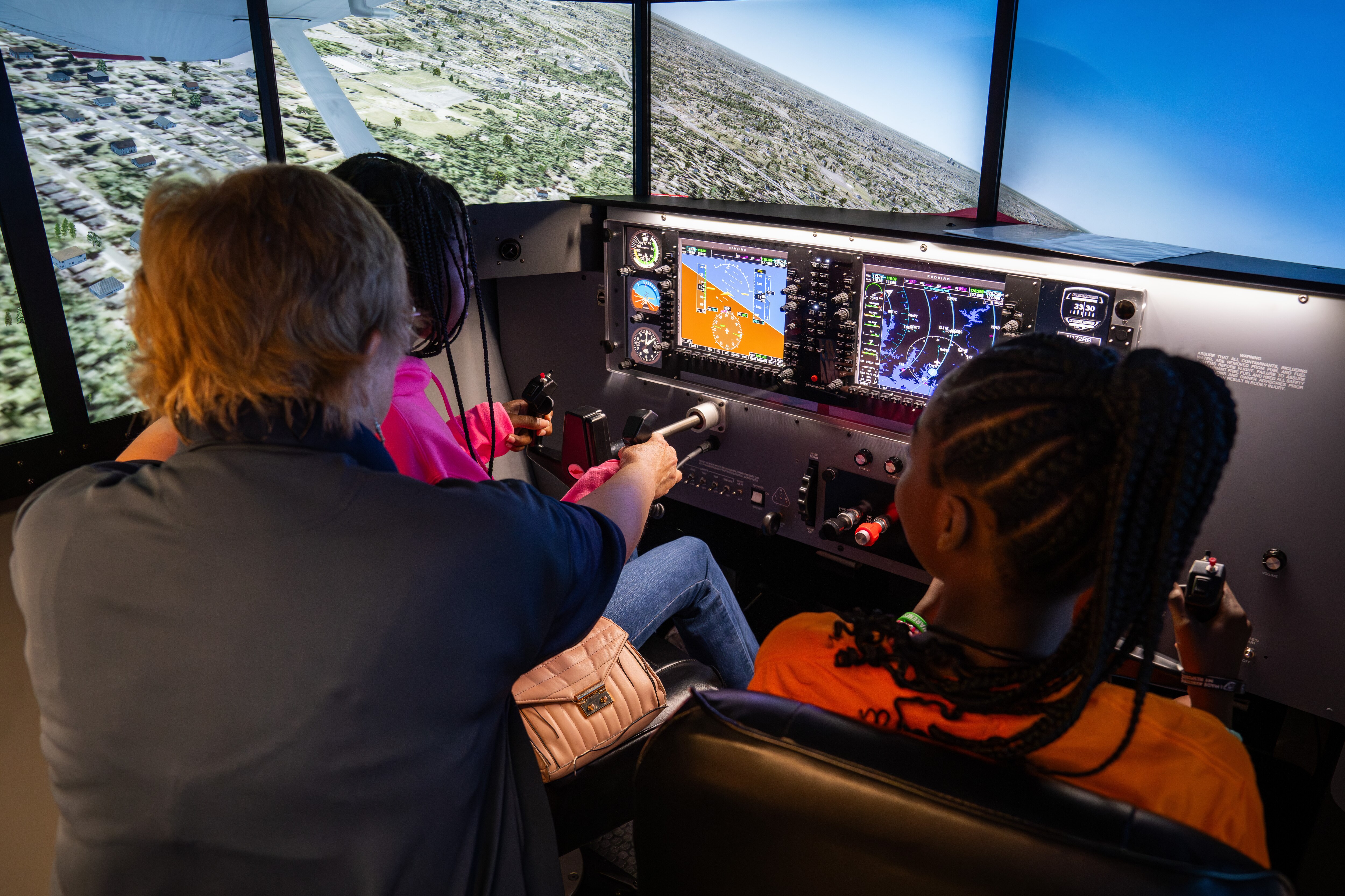 Instructor Jane Toskes shows campers Tori and Lauren how to fly a plane simulation.