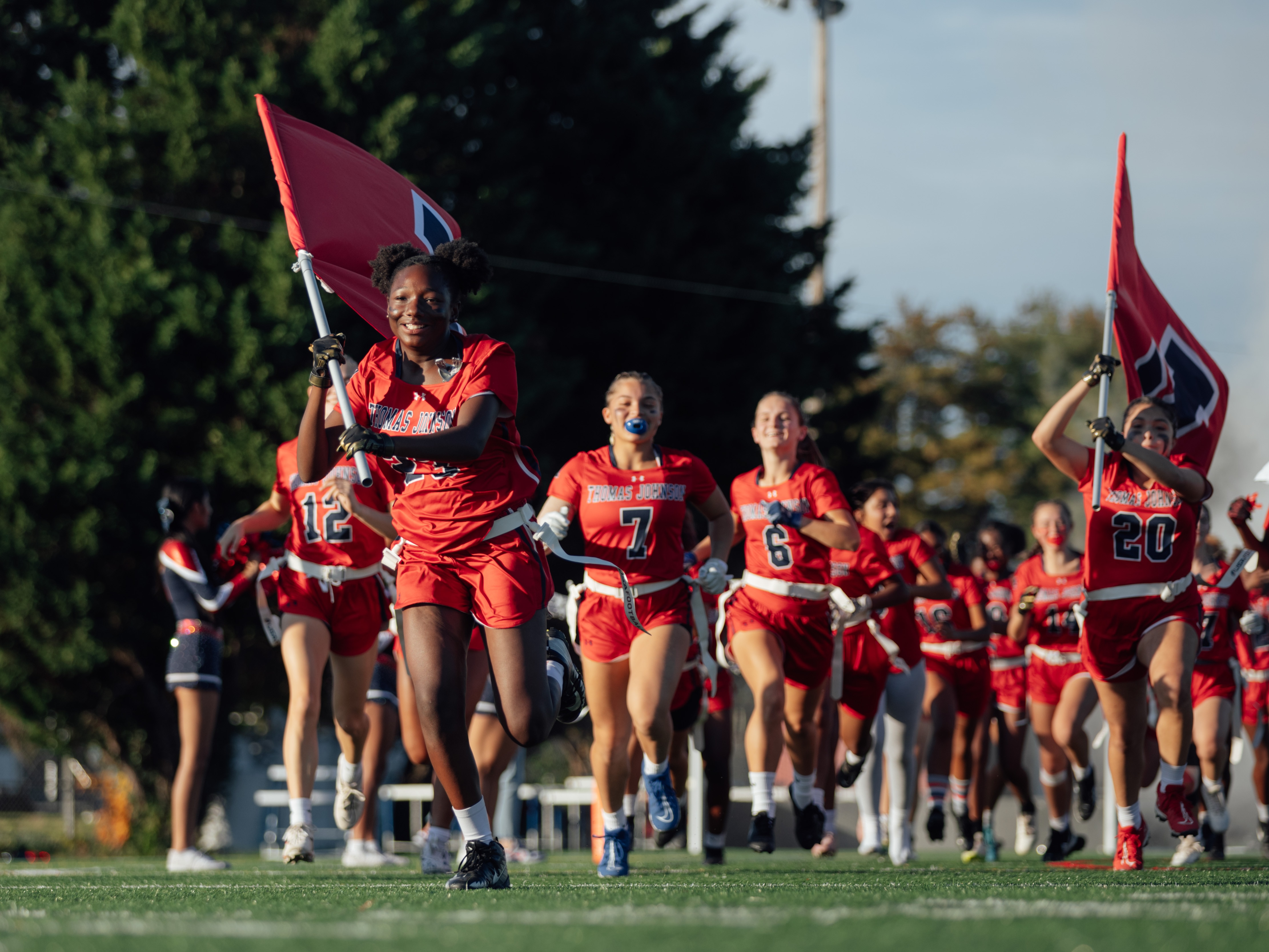 Jayana Lloyd, left, leads the Thomas Johnson Patriots flag football team onto the field before a game against the Frederick County Cadets in the last regular season game of the girls flag football season at Frederick County Public Schools, on Thursday, Oct. 26, 2023 in Frederick, MD. The Baltimore Ravens helped fund the FCPS girls flag football pilot program this year. (Wesley Lapointe / for the Baltimore Banner)