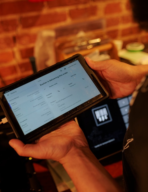 Evan Weinstein, owner of Underground Pizza, holds a screen showing takeout orders at the downtown location.