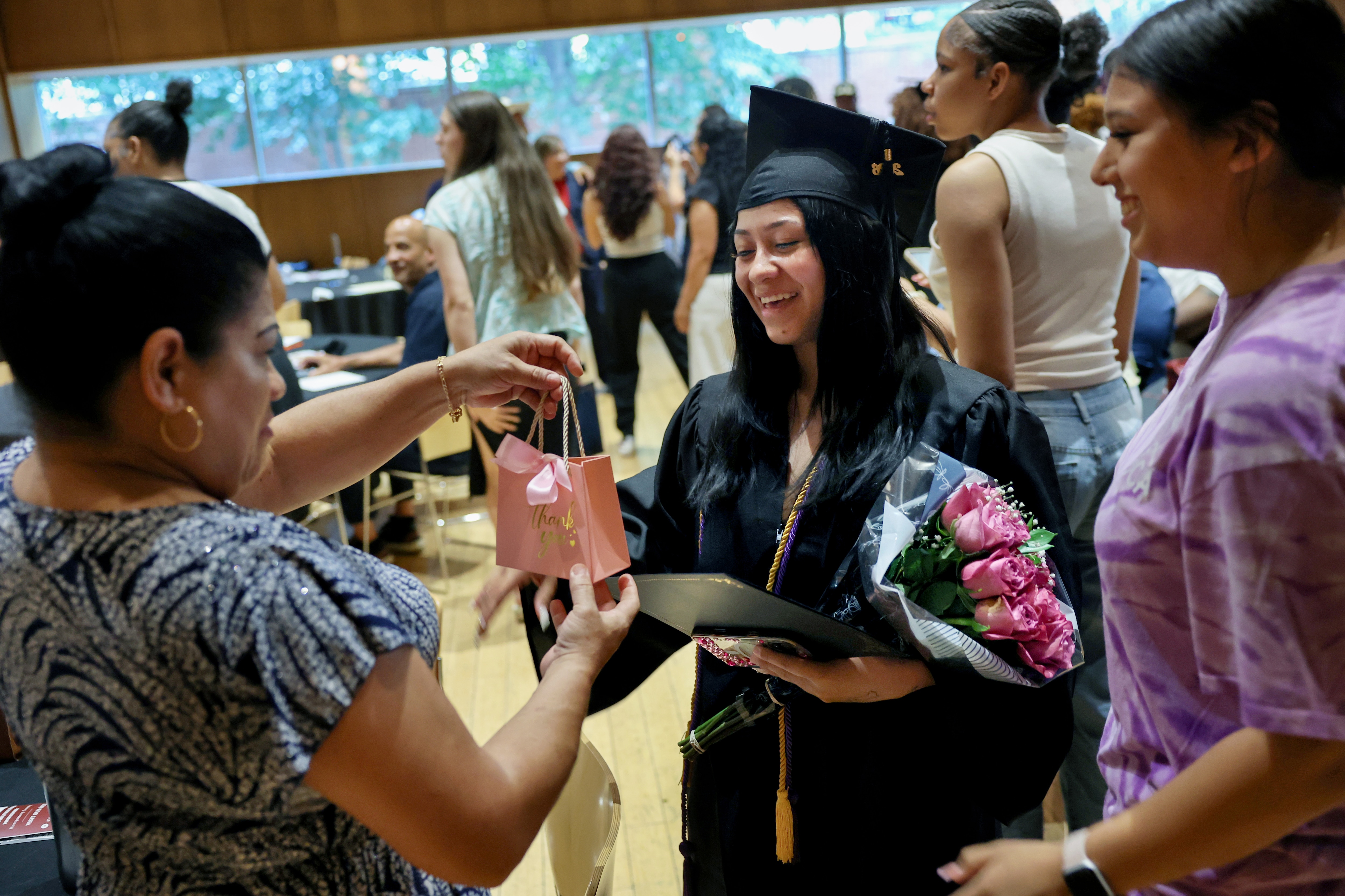 Julissa Mejia receives a celebratory gift from her mother Gloria Lovo after Mejia received her GED diploma during the Maryland Multicultural Youth Center 2025-2026 graduation ceremony at the Silver Spring Civic Building in Silver Spring, Maryland, U.S., June 30, 2026.
